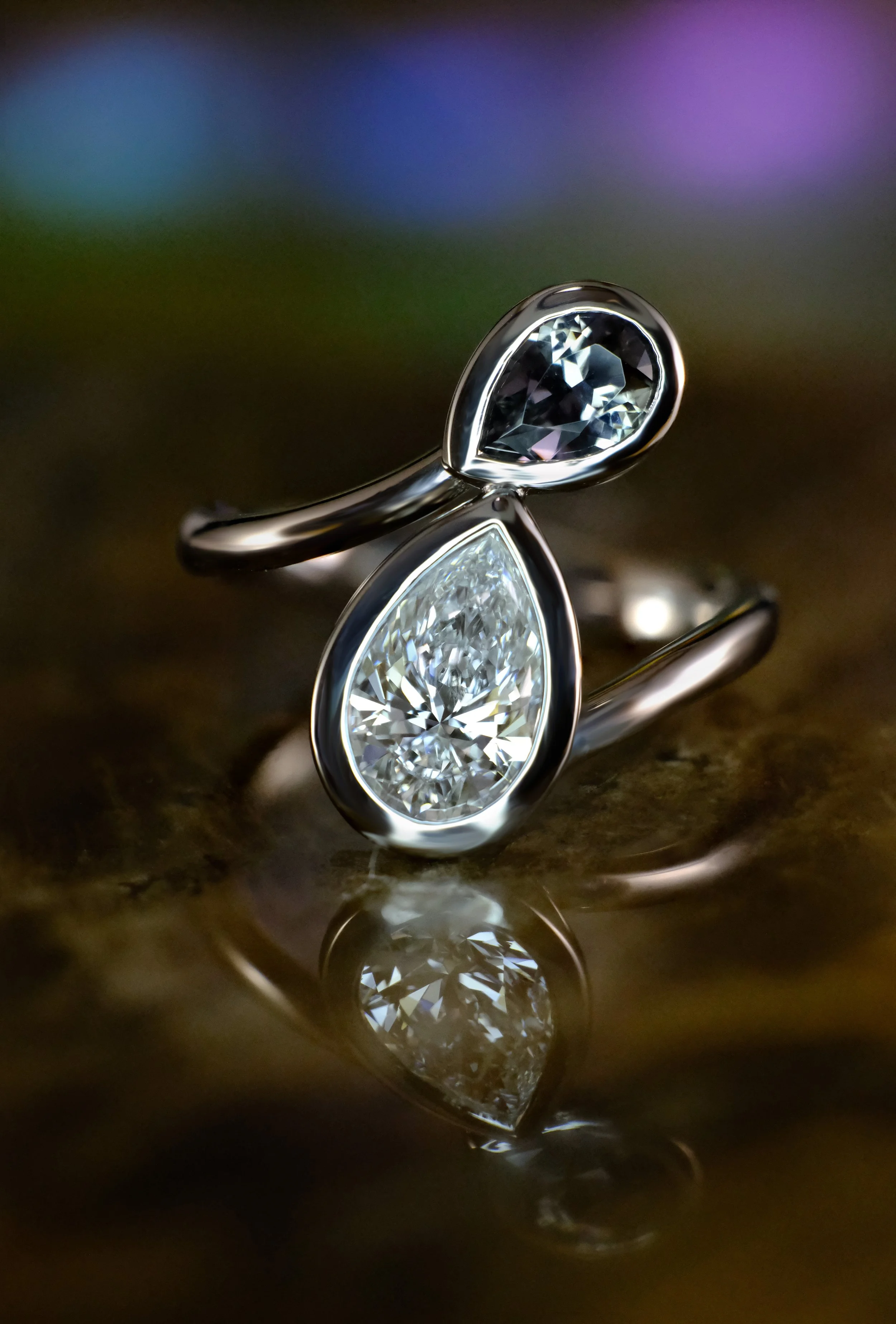 White gold bypass ring featuring two pear-shaped diamonds set opposite each other, with a polished band and reflective surface.