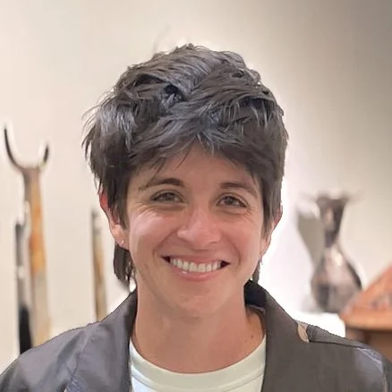 Young person with short, tousled dark hair smiling indoors.