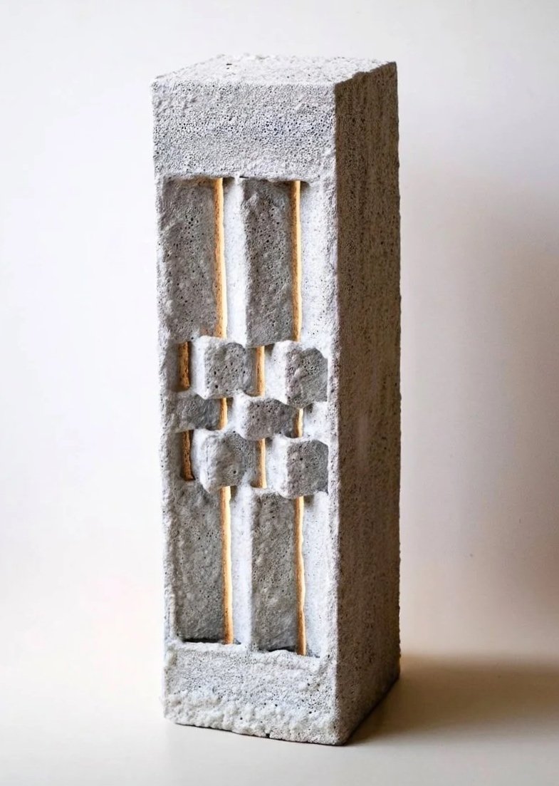 Concrete block with aligned sticks and small concrete cubes embedded, resembling a miniature fence.