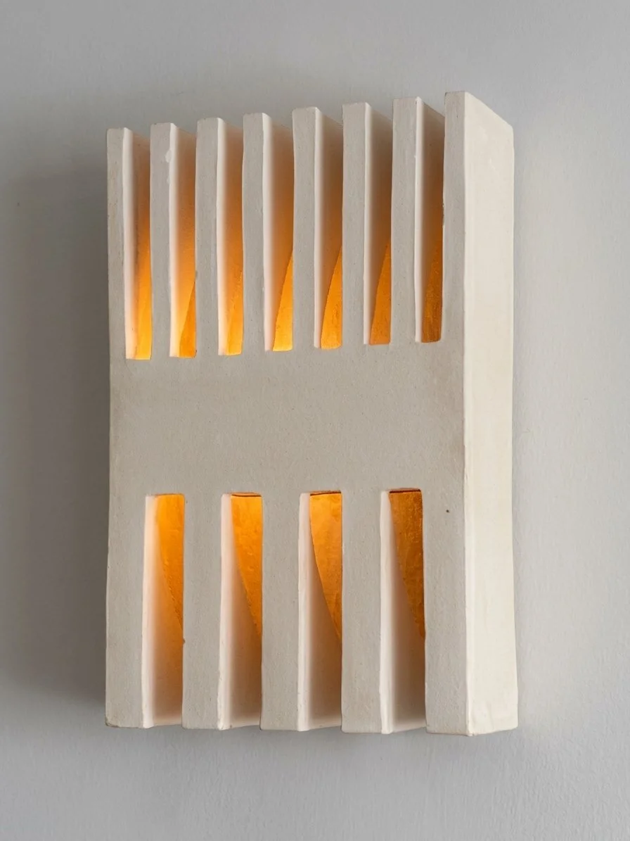Modern wall sconce with vertical slats and warm orange lighting