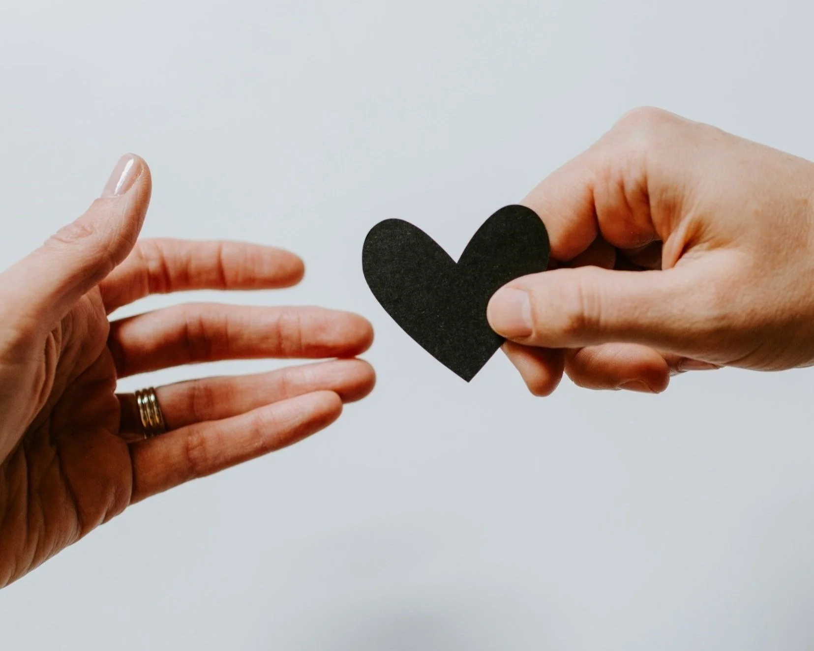 one hand handing another a heart