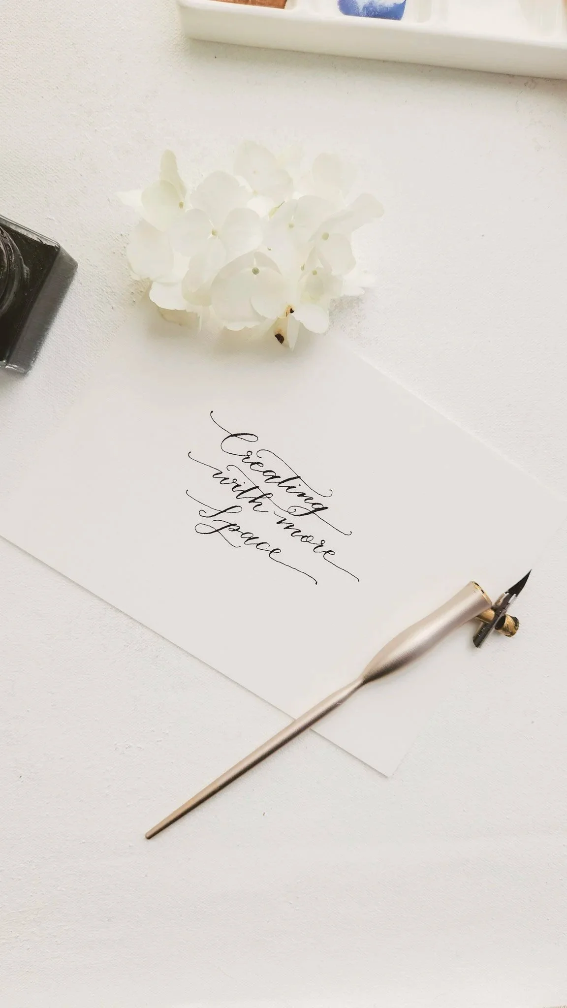 white envelope with black calligraphy writing' creating with more space' also with a gold calligraphy pen on desk.