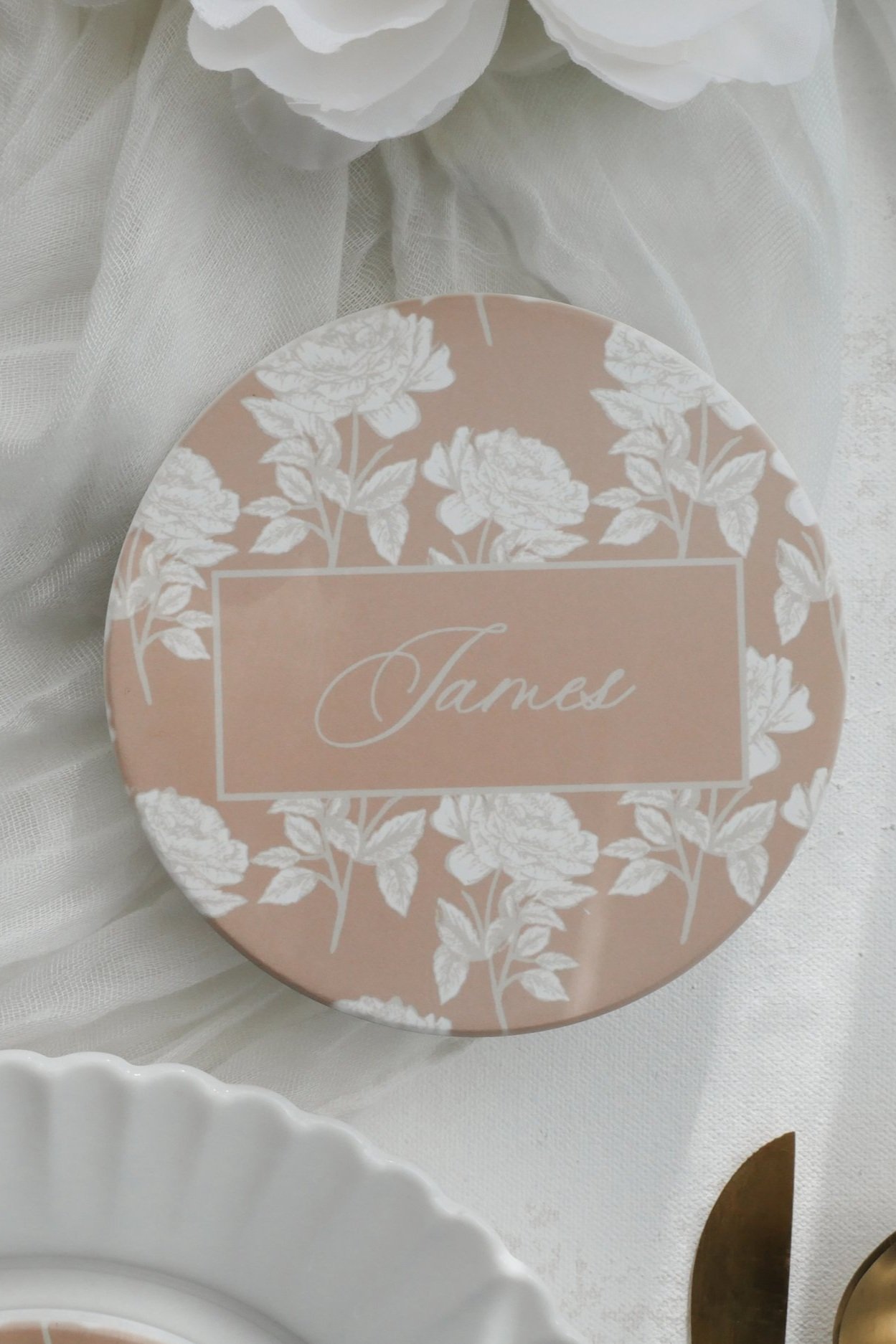 Close up of Blushing rose coaster on white plates for wedding