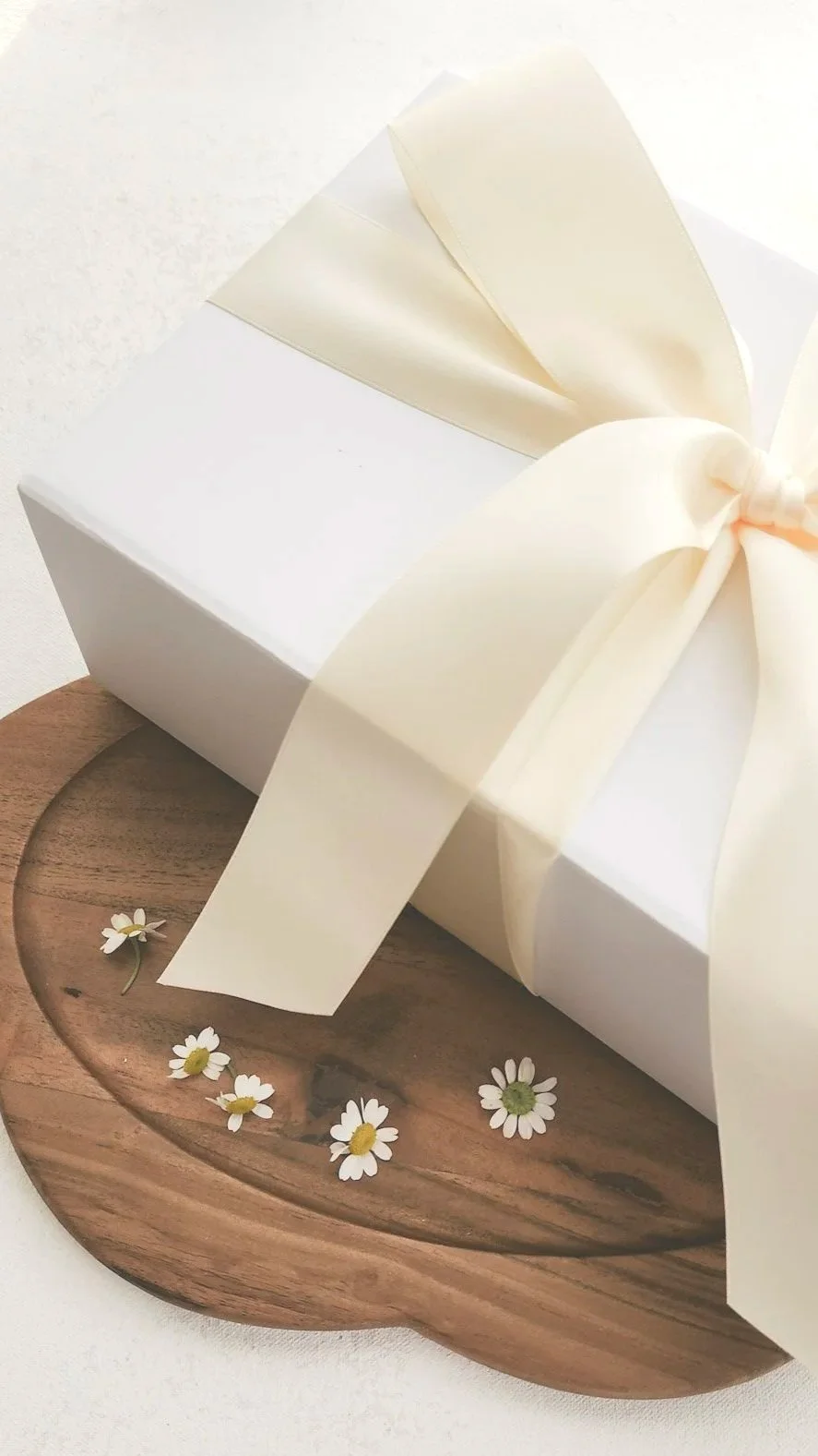 White Gift boxes wrapped in cream satin ribbon on brown wooden dish