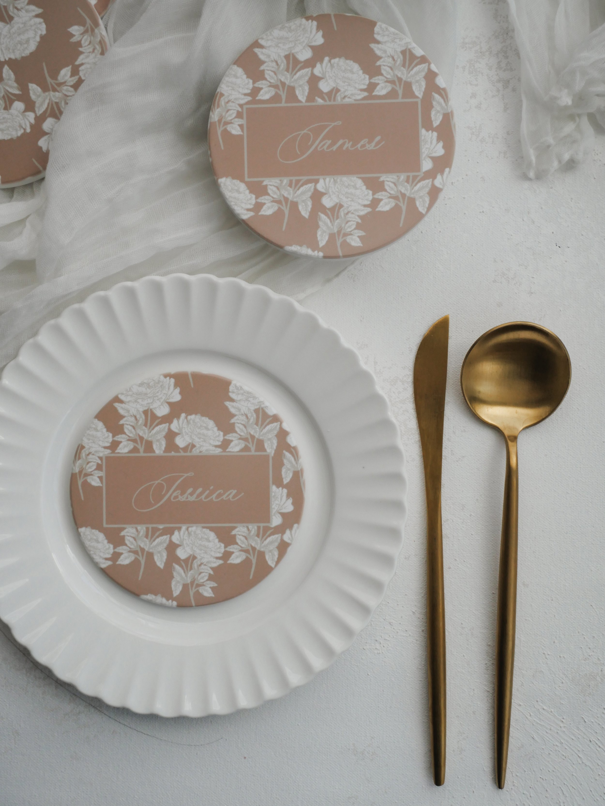 Blushing rose coasters on white plates for wedding