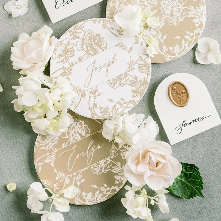 Wedding coasters and floral decorations on a table, with name cards  'Joseph' and 'Evelyn,' and a card marked 'James' with a wax seal.