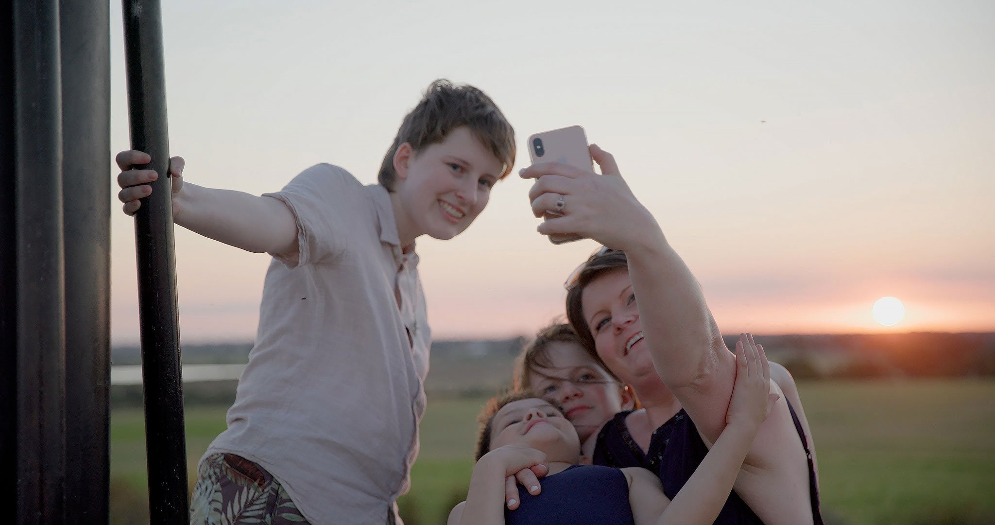 Anthea takes a selfie with Aether, Hayley and William. They are at a park and the sun is setting in the background (Copy)