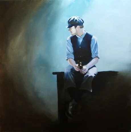 A young man sitting alone on a bench in a dimly lit area, looking at his phone, wearing a newsboy cap, light blue shirt, and dark vest.