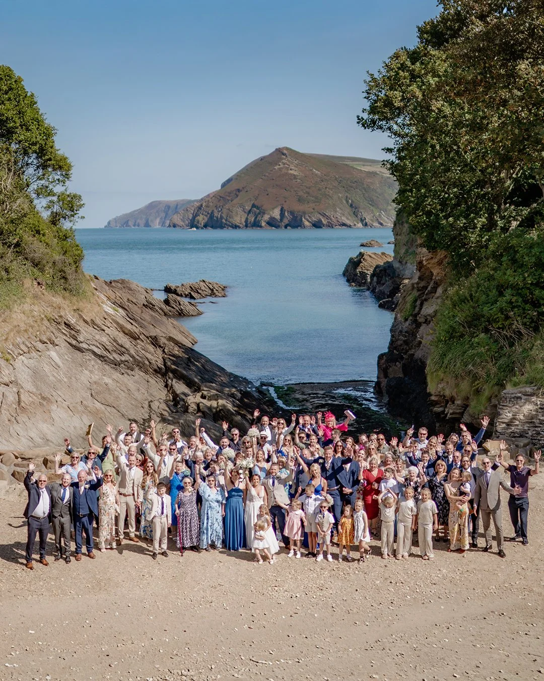 Bride Back to Camera in silk wedding dress  looking over grooms shoulder  at a rolling hillside. Groom looking ahead in a checked wooden suit his hand of the brides back. 