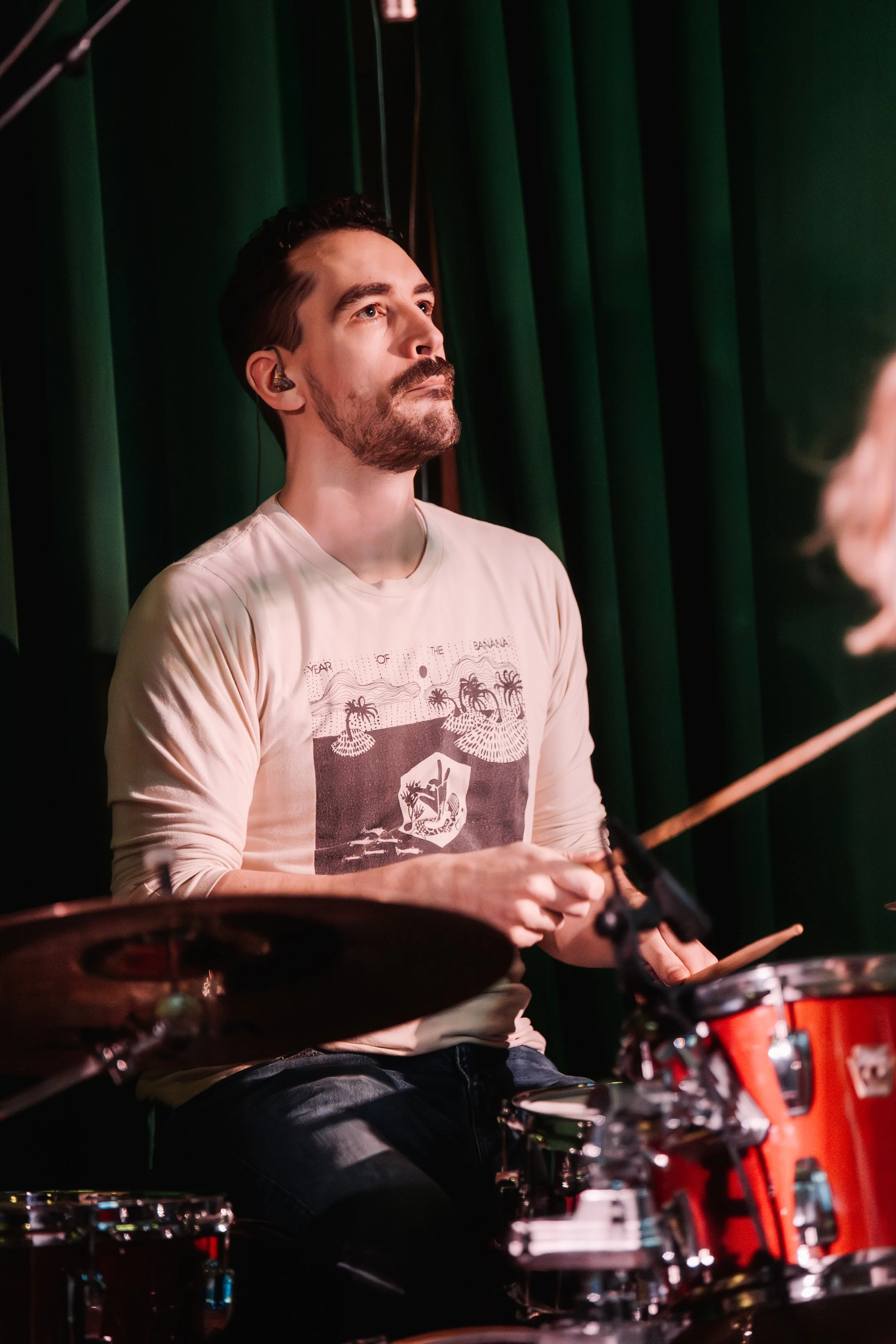 A man playing drums in a recording studio with wooden walls and soundproofing equipment.