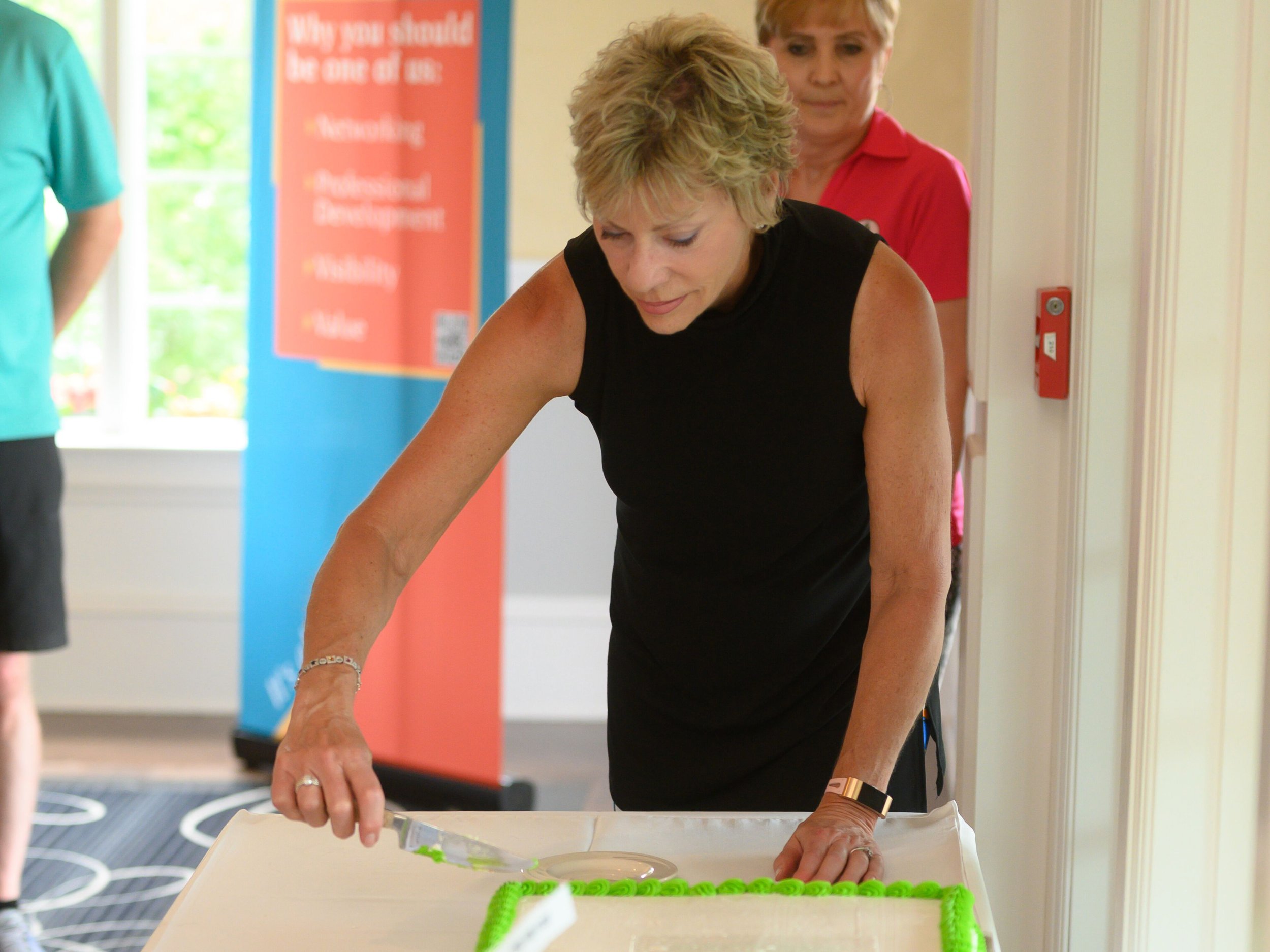 Francine cuts the cake in celebration of Junior Achevement's 100th anniversary