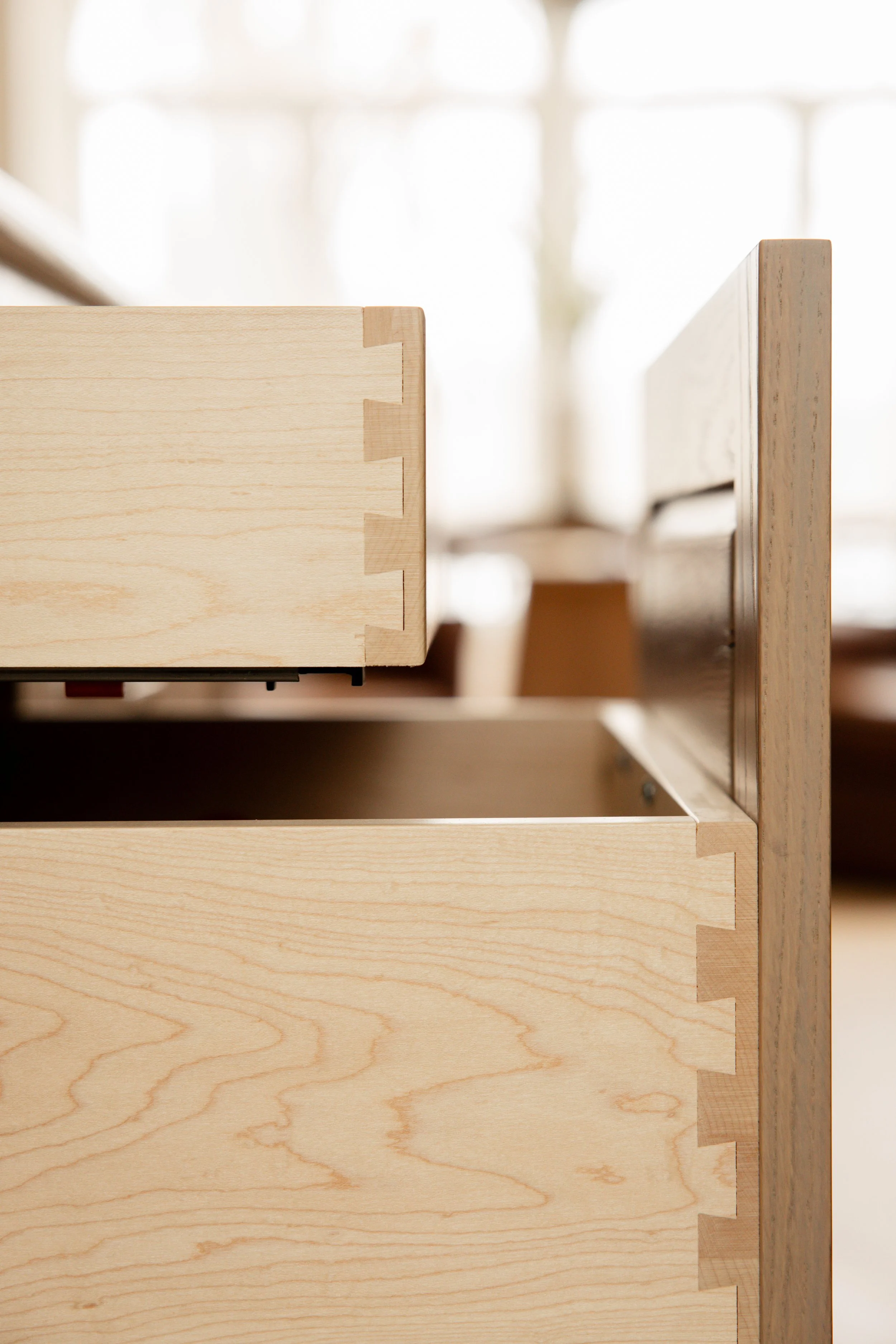 Person chopping a red bell pepper on a wooden cutting board, with a small dish of sliced onions nearby, in a kitchen.