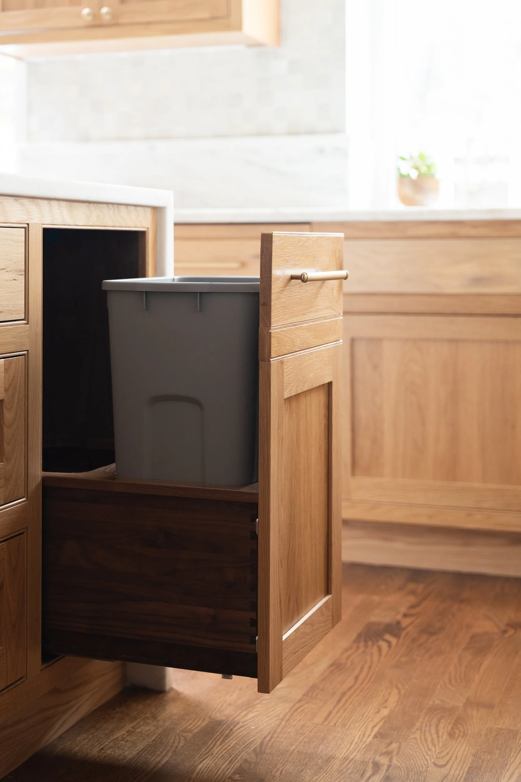 Close-up of a kitchen cabinet with wooden door panels, showing a section of a countertop and some white containers.