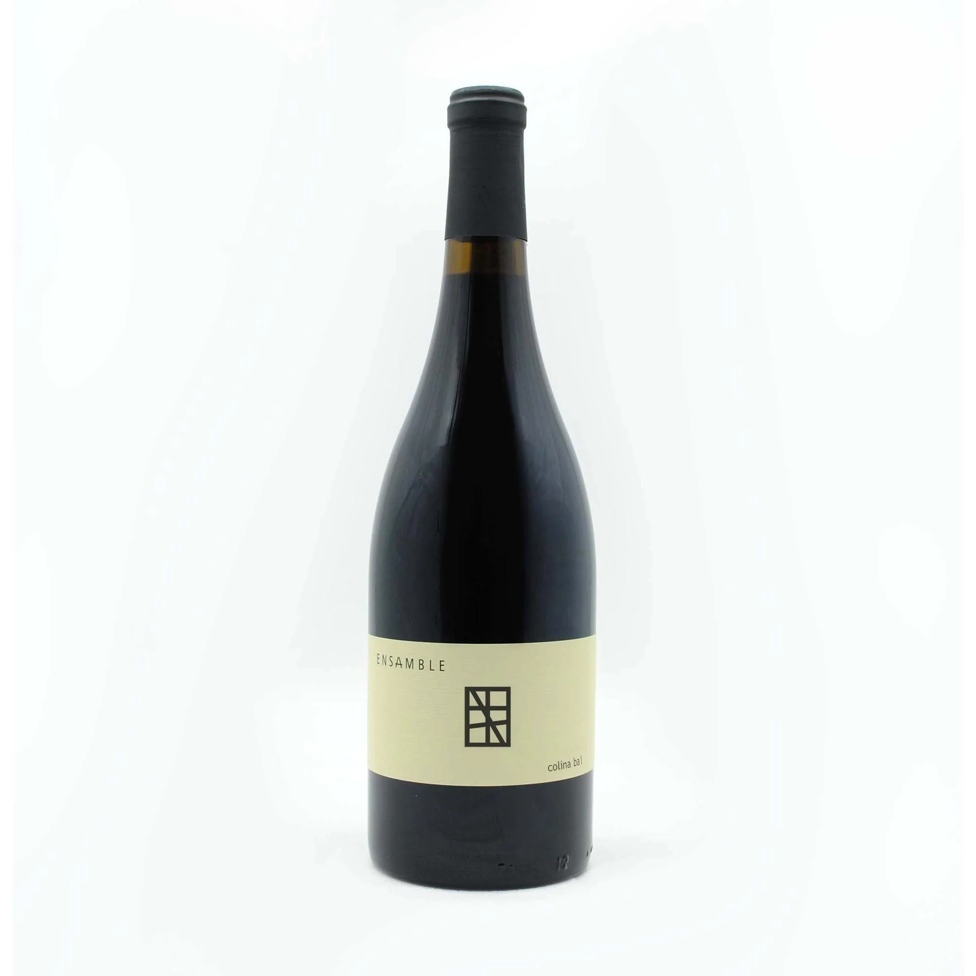 A dark glass wine bottle with a black cap and an off-white label that reads 'Ensemble' and 'colina bal' with a simple black geometric logo on a white background.