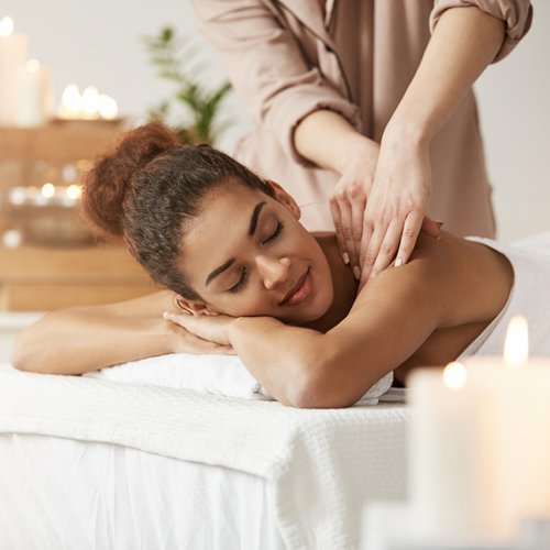 woman getting massage in brightly lit setting; eyes clothes, very relaxed