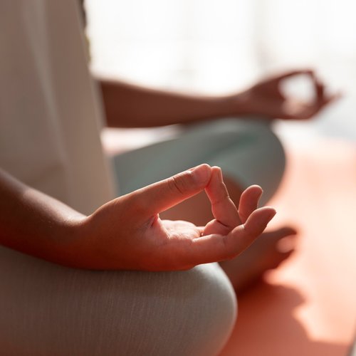 person sitting cross legged on orange yoga mat in meditative posture