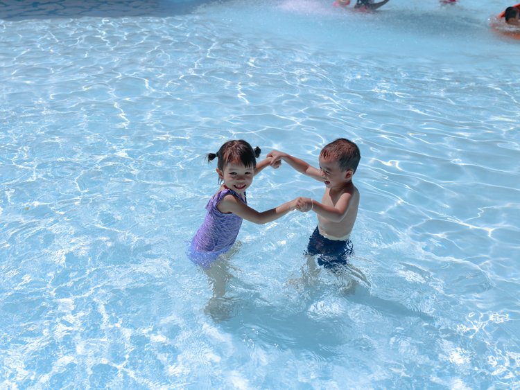 a young boy and girl playing and laughing together in a large pool
