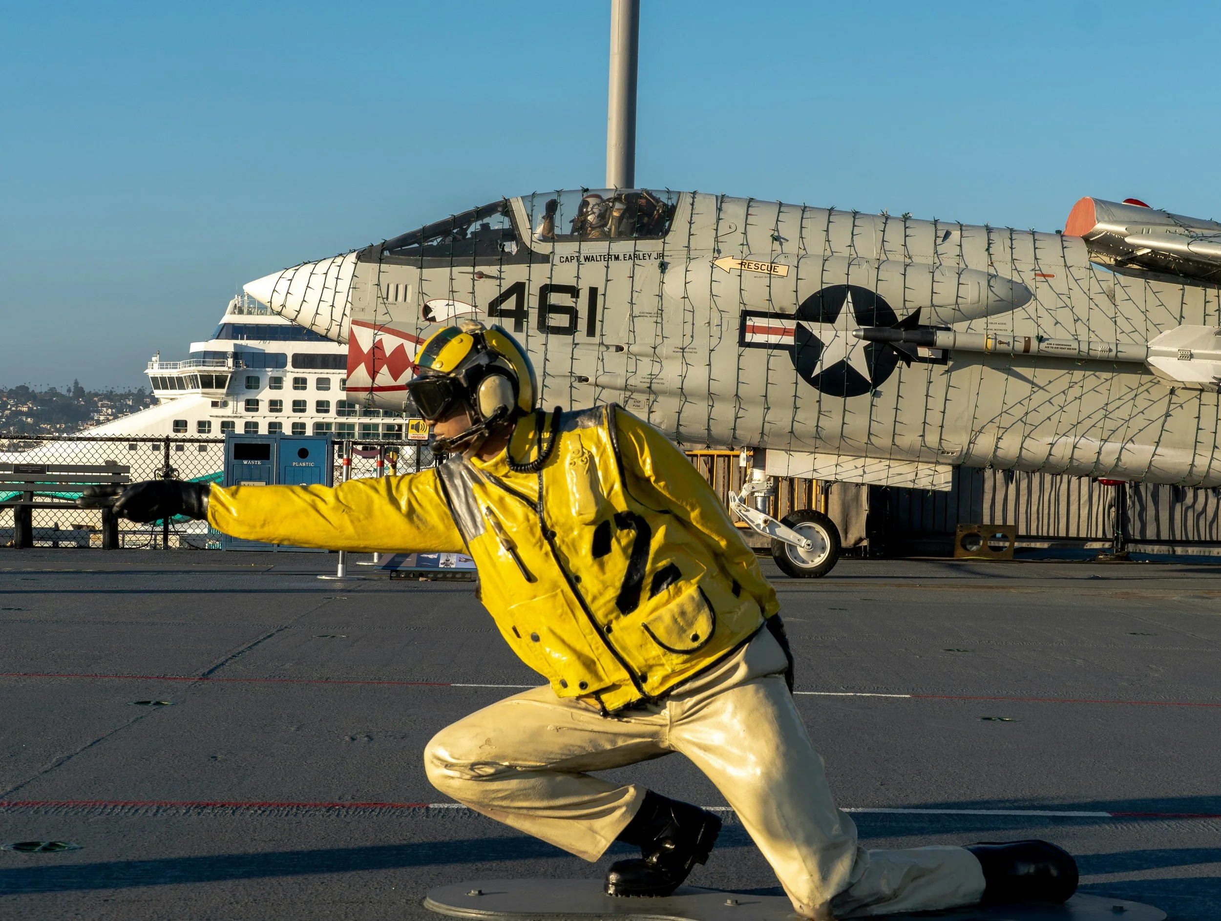 A model of a man pointing for take off on the flight deck of the USS Midway. A plane is behind him.