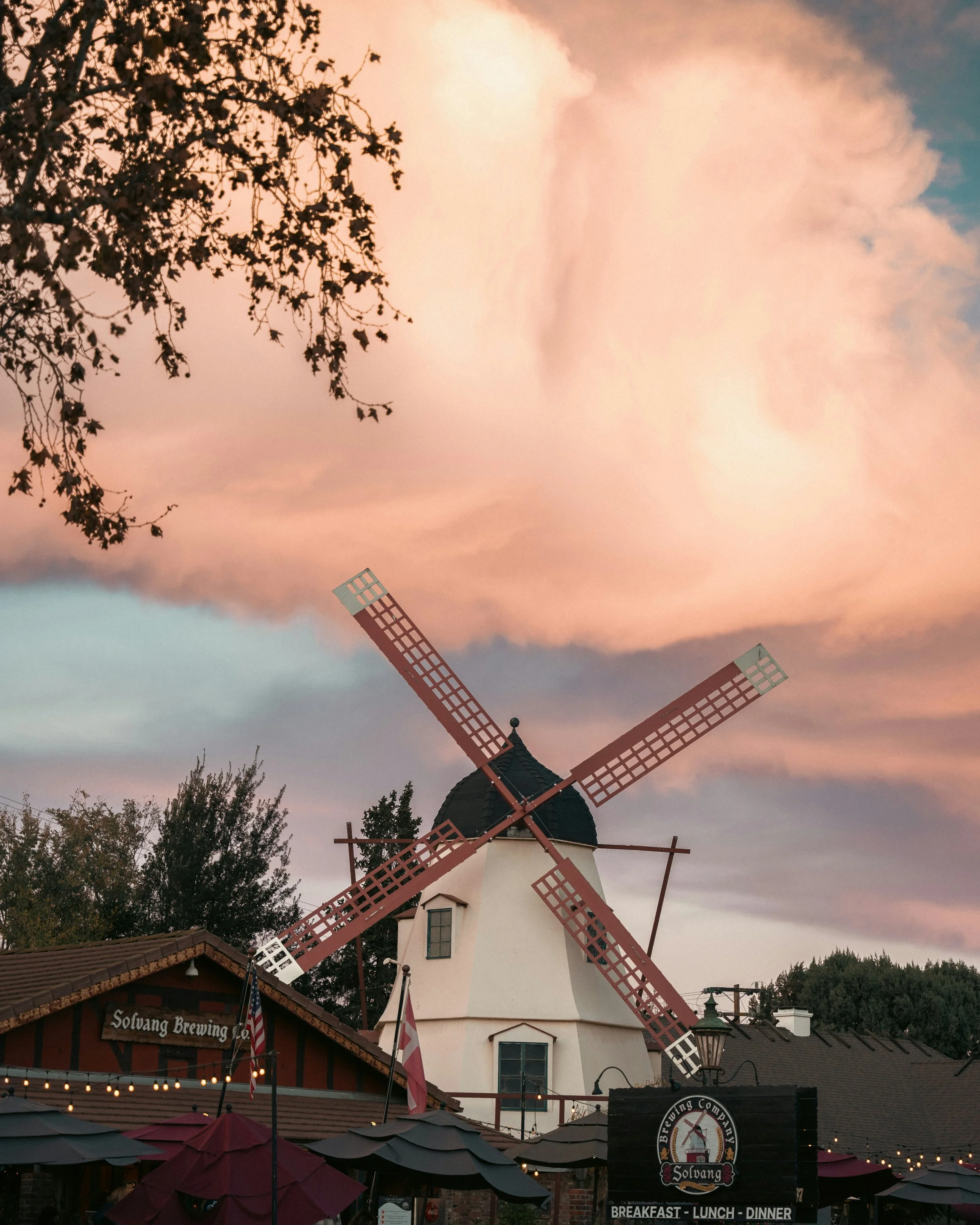 A large, fluffy cloud floats in the sky over a white windmill in Solvang, California