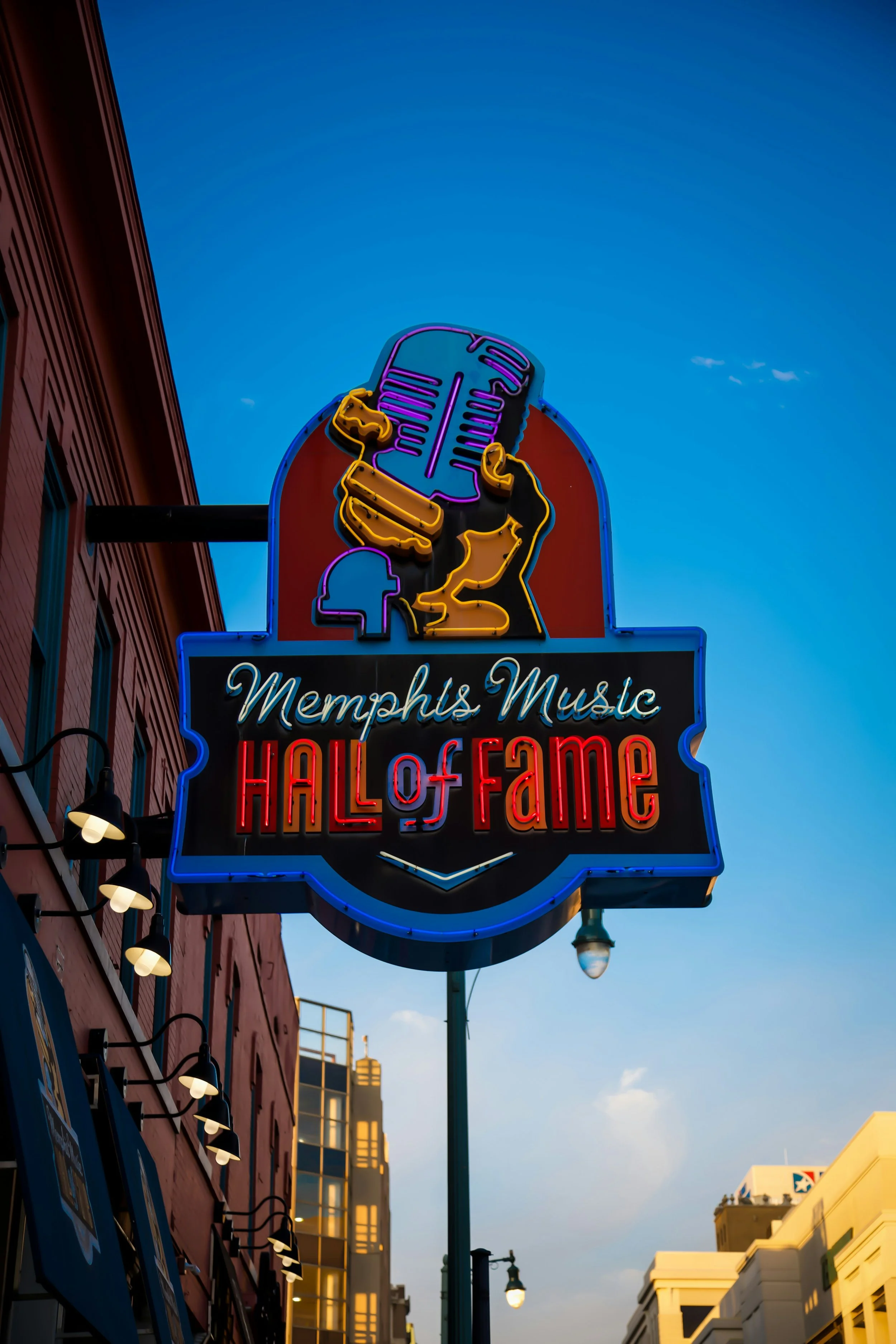 A neon sign shows a hand holding a microphone. It reads: Memphis Music Hall of Fame. Drives & Detours Memphis walking tour