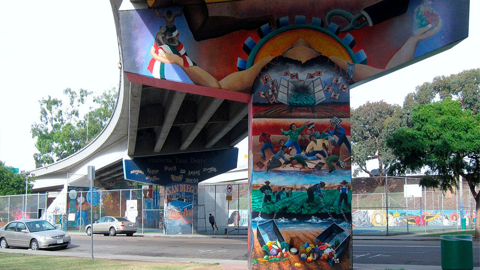 Graffiti on the supports of the freeway over Chicano Park, Barrio Logan, San Diego. It shows migrant workers in the fields and protesting