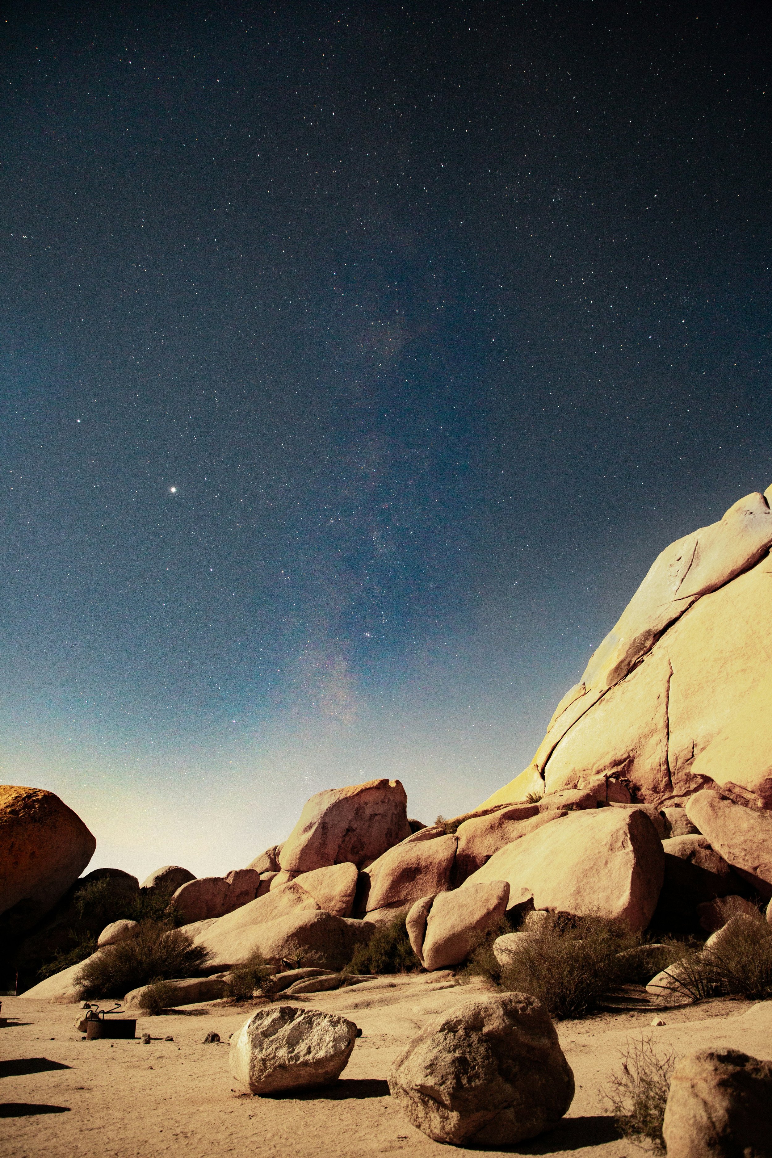 The Milky Way can be seen over a rock formation in Joshua Tree National Park. The dark sky is full of stars, too many to count