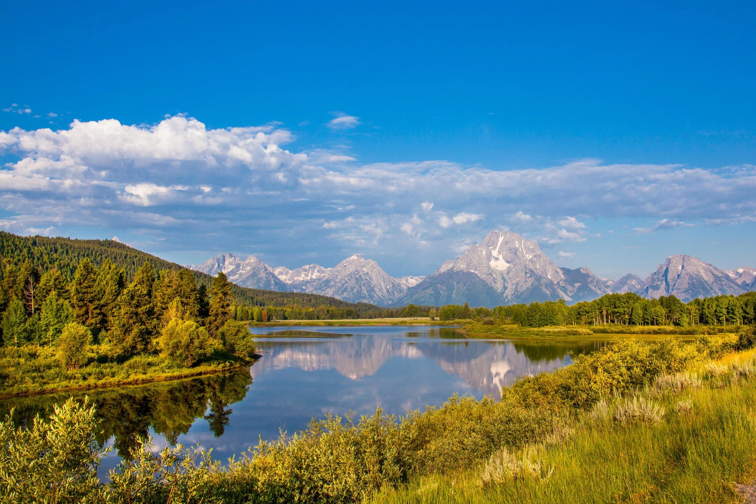 A river flows the plains under some craggy mountains. Drives & Detours Yellowstone local tips
