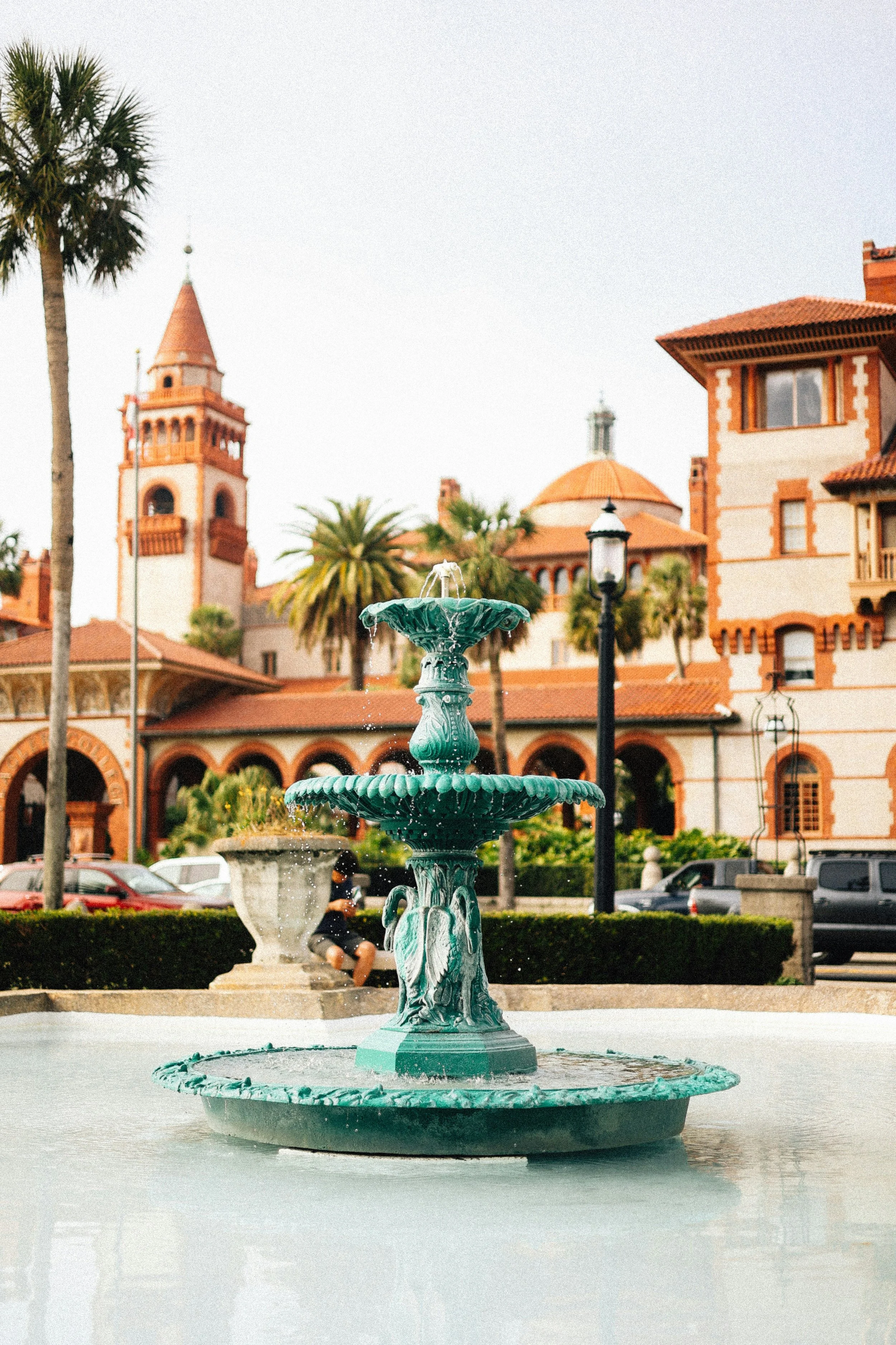 Water pours out of a green fountain in front of one of St. Augustine's Spanish Colonial-style buildings
