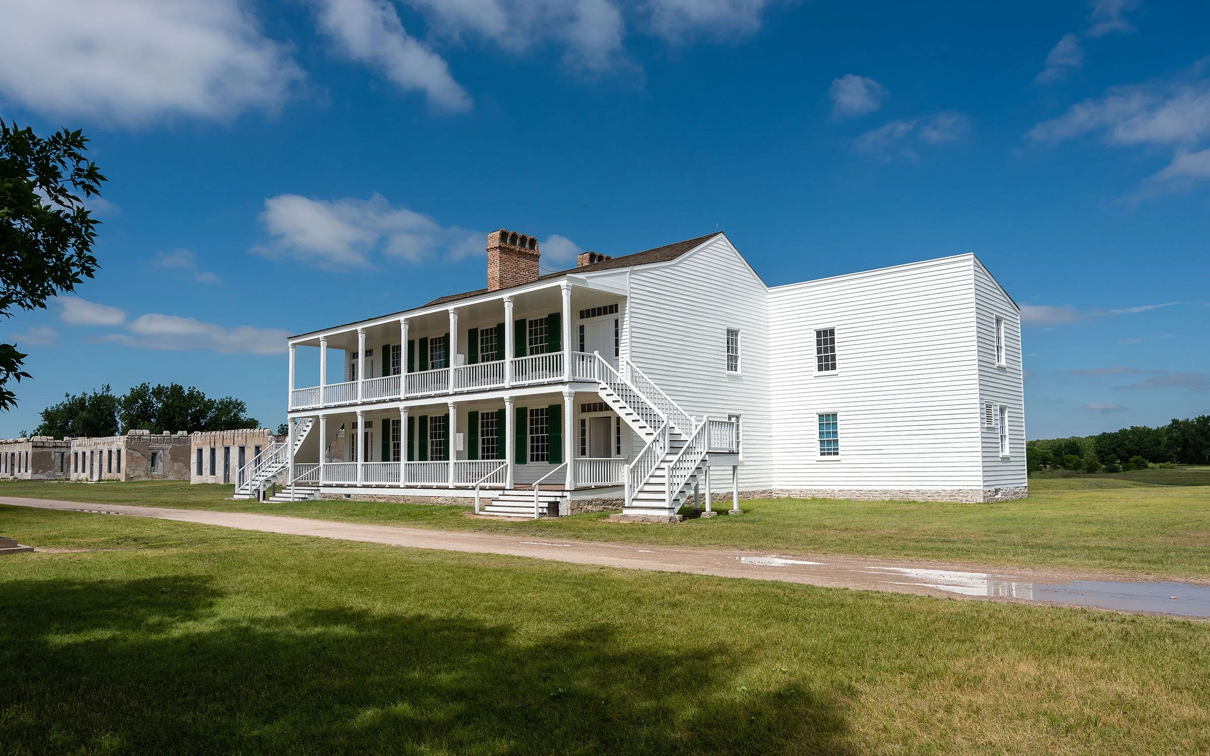 The large, white wooden building of Old Bedlam against a blue sky in Fort Laramie, Wyoming