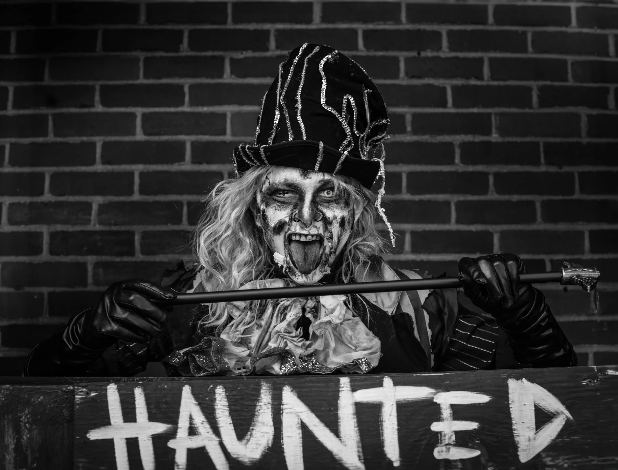 A person dressed as a witch stands over a sign reading "Haunted" in Salem, Massachusetts. Drives & Detours Salem self-guided tour