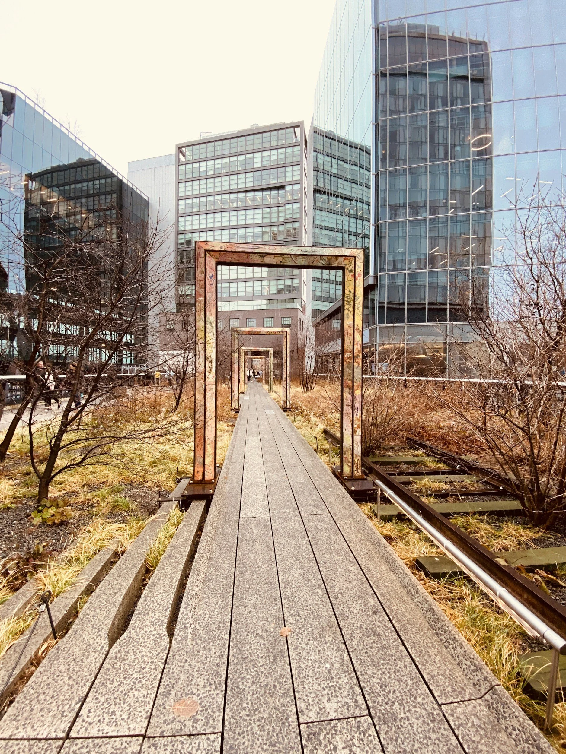 Large doorframes surround the path by the railway in the High Line Park, New York, and skyscrapers rise in the distance. Drives & Detours New York High Line walking tour