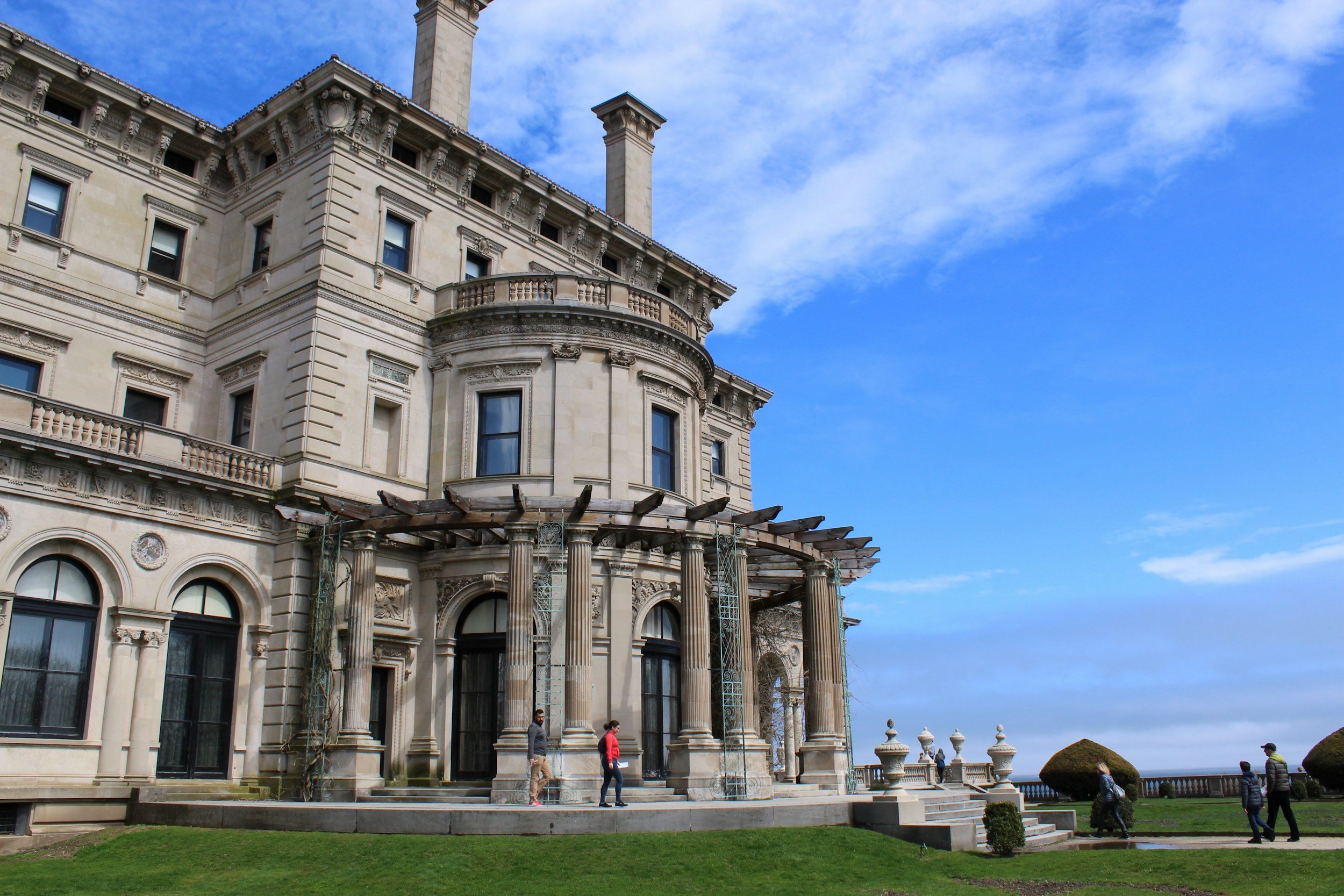People walk around the huge edifice of the Breakers under a blue sky. Drives & Detours things to do in Newport