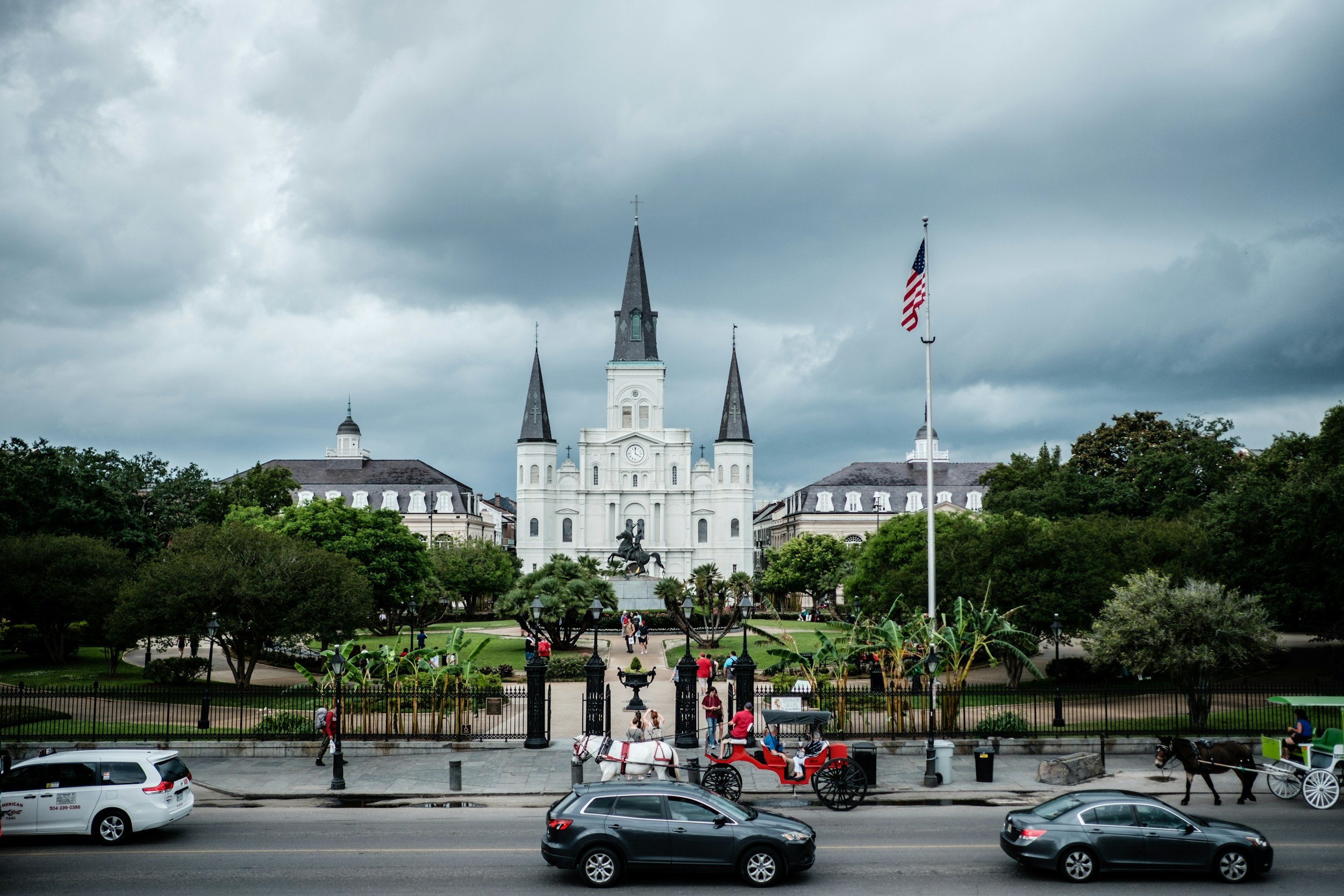 Tourists pose outside the majestic St Louis Cathedral, Jackson Square for photos. A horse and carriage waits outside. Drives & Detours French Quarter walking tour