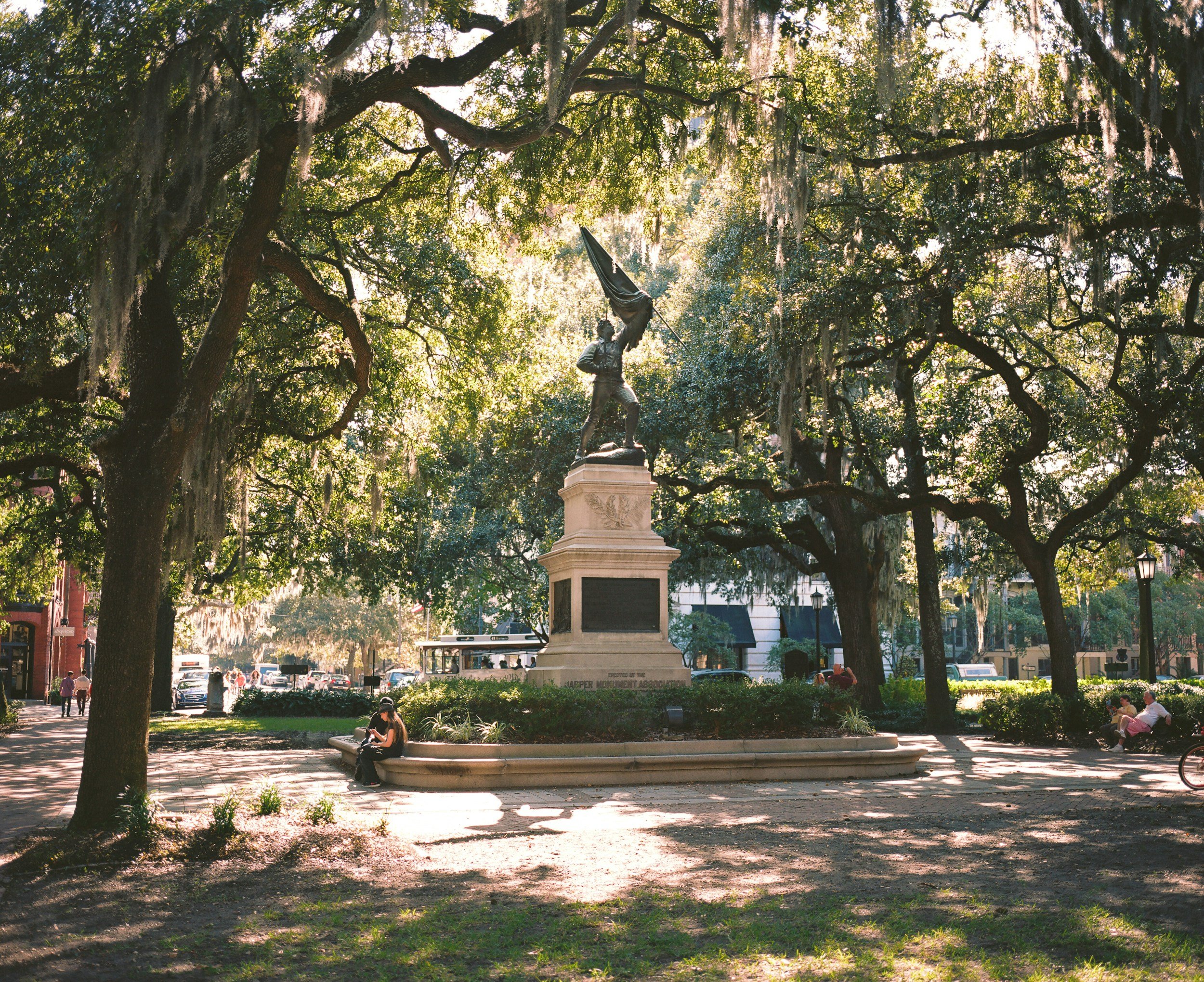 A statue of a man flying a flag under live oaks in a square in Savannah, GA