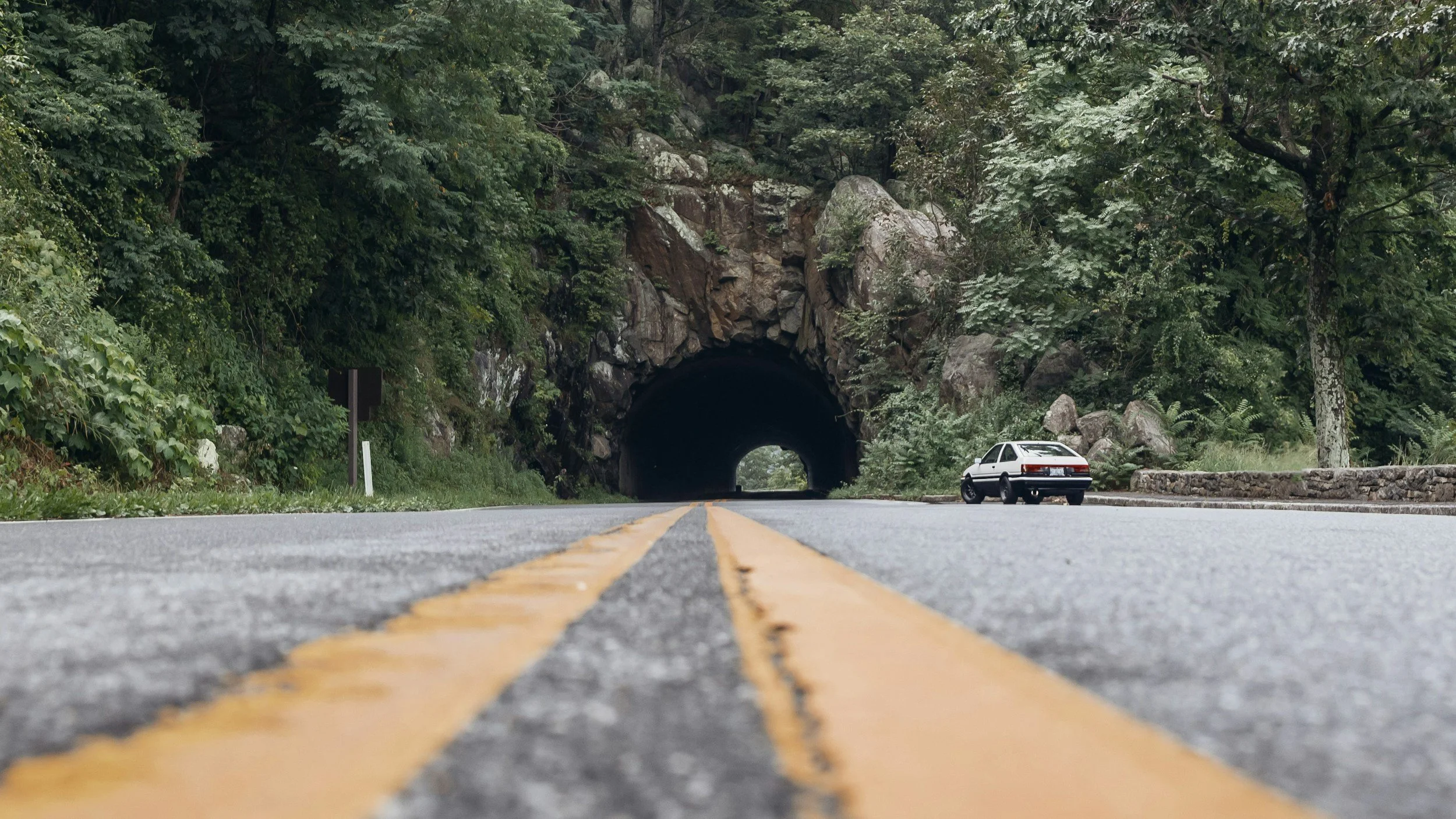 A car sits by a tunnel covered in forest near Front Royal, on Skyline Drive. Drives & Detours best restaurants near Shenandoah National Park