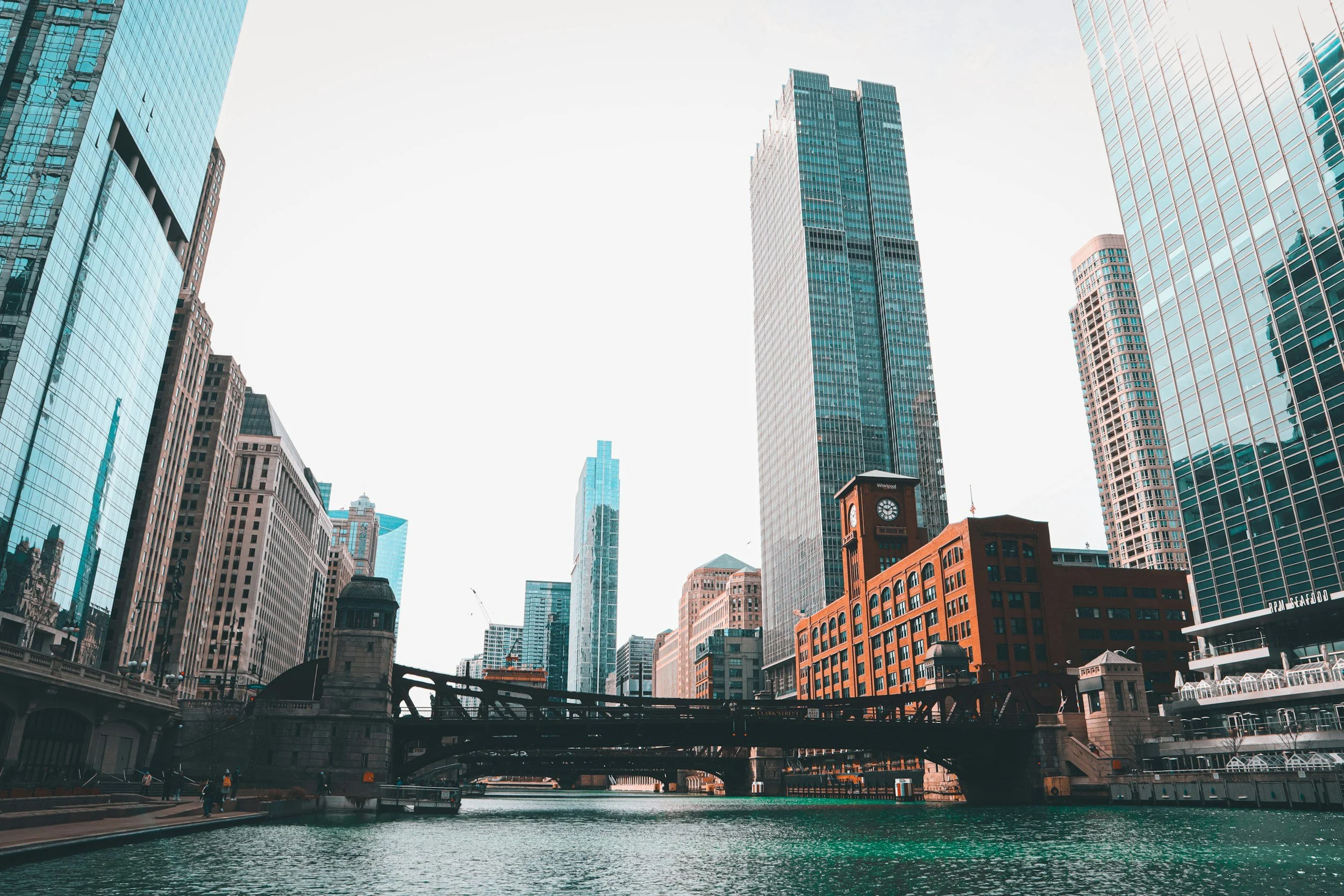An old bridge crosses the Chicago River beside a red brick building