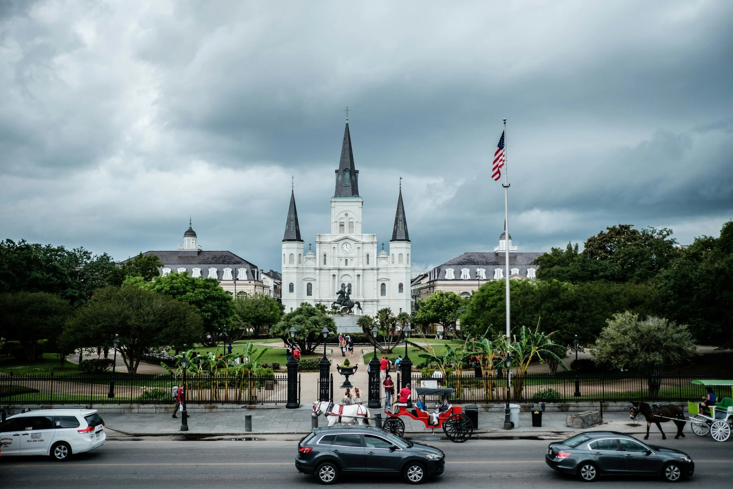 Tourists pose outside the majestic St Louis Cathedral, Jackson Square for photos. A horse and carriage waits outside. Drives & Detours French Quarter 2027 Guide