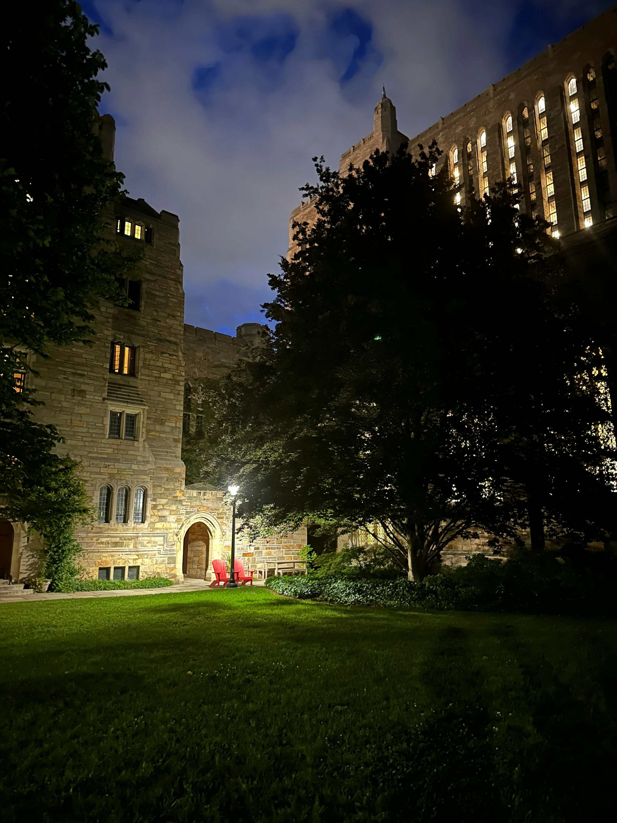 One of the greens in New Haven, Connecticut, at night. Some red deck chairs are lit up by a streetlight. Drives & Detours Yale Campus Tour