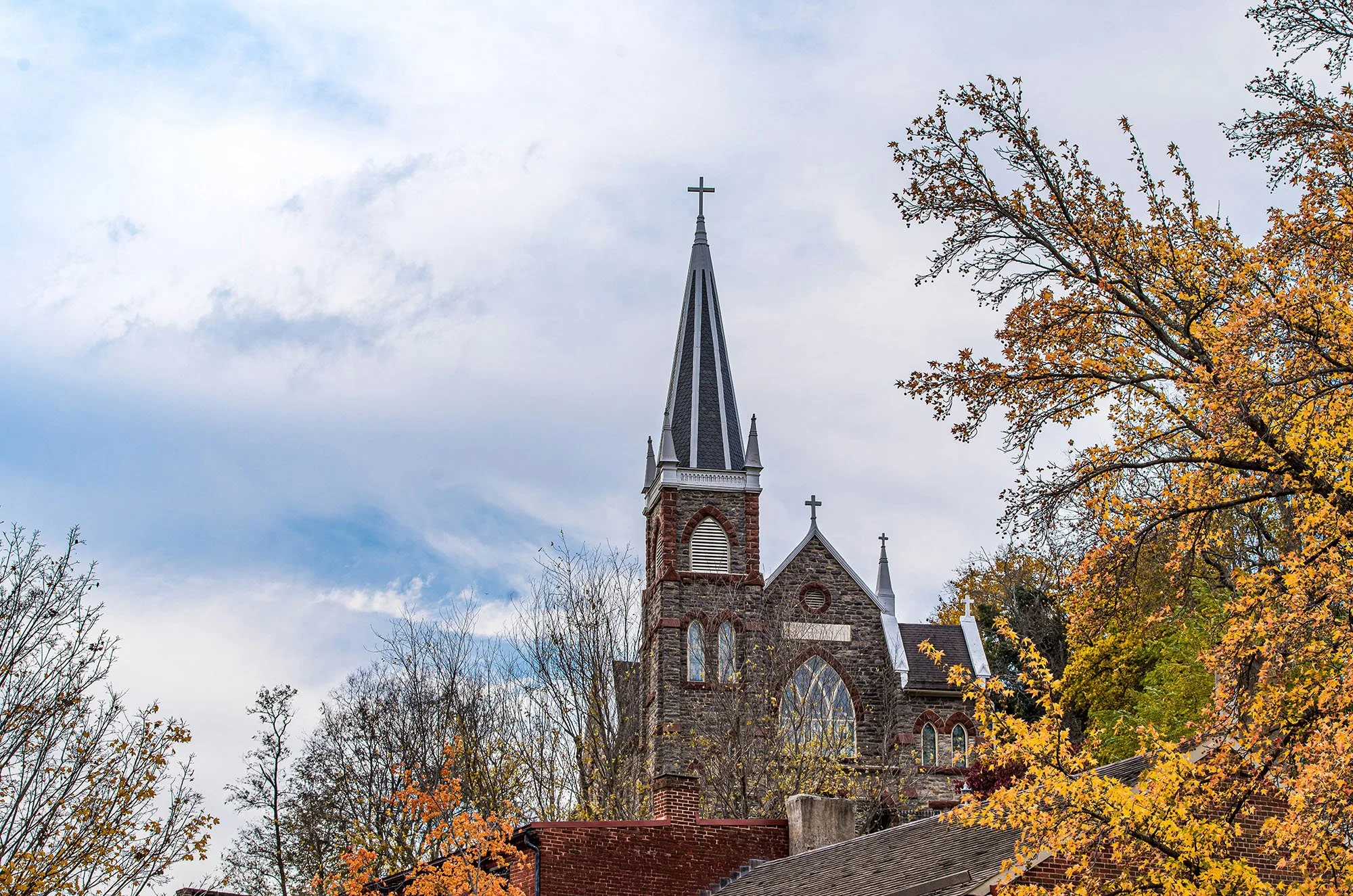 The stone St. Peter’s Roman Catholic Church stands on top of a hill surrounded by fall foliage