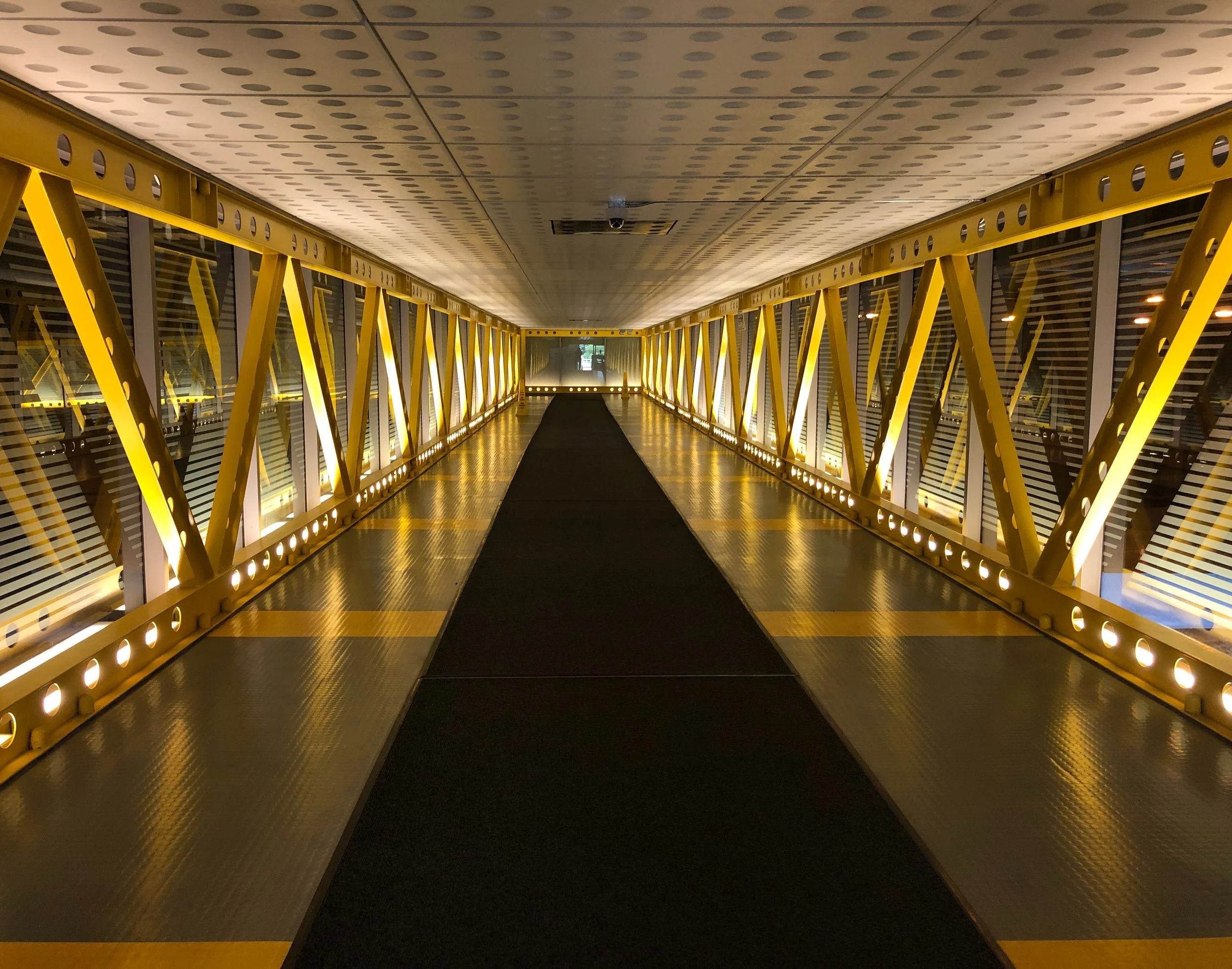 A steel yellow covered bridge is lit up at night on the Pedway. Drives & Detours Chicago hidden gems