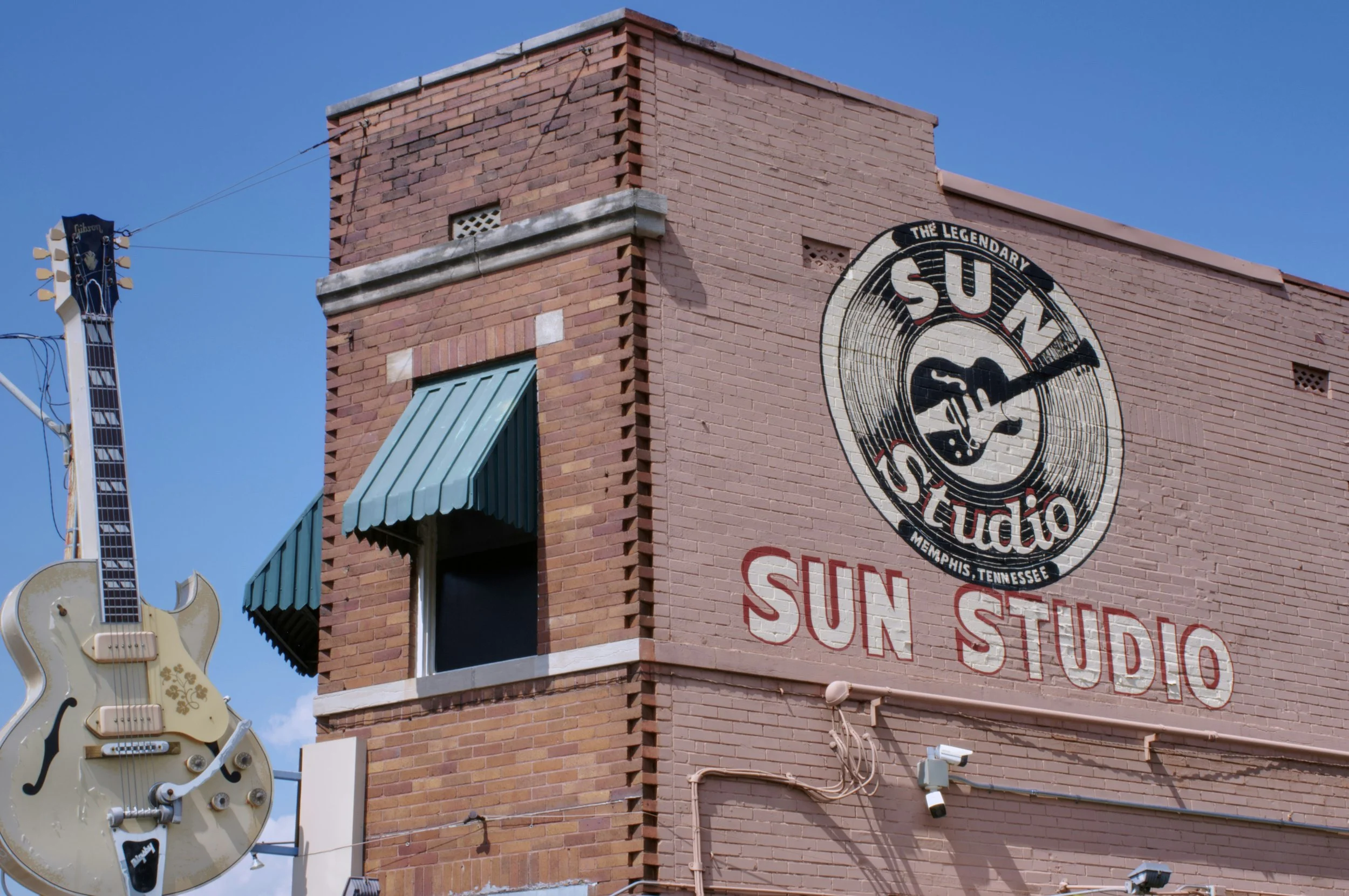A brick building with the Sun Studio logo on the side, and a huge cream Les Paul guitar beside it. Drives & Detours Memphis walking tour