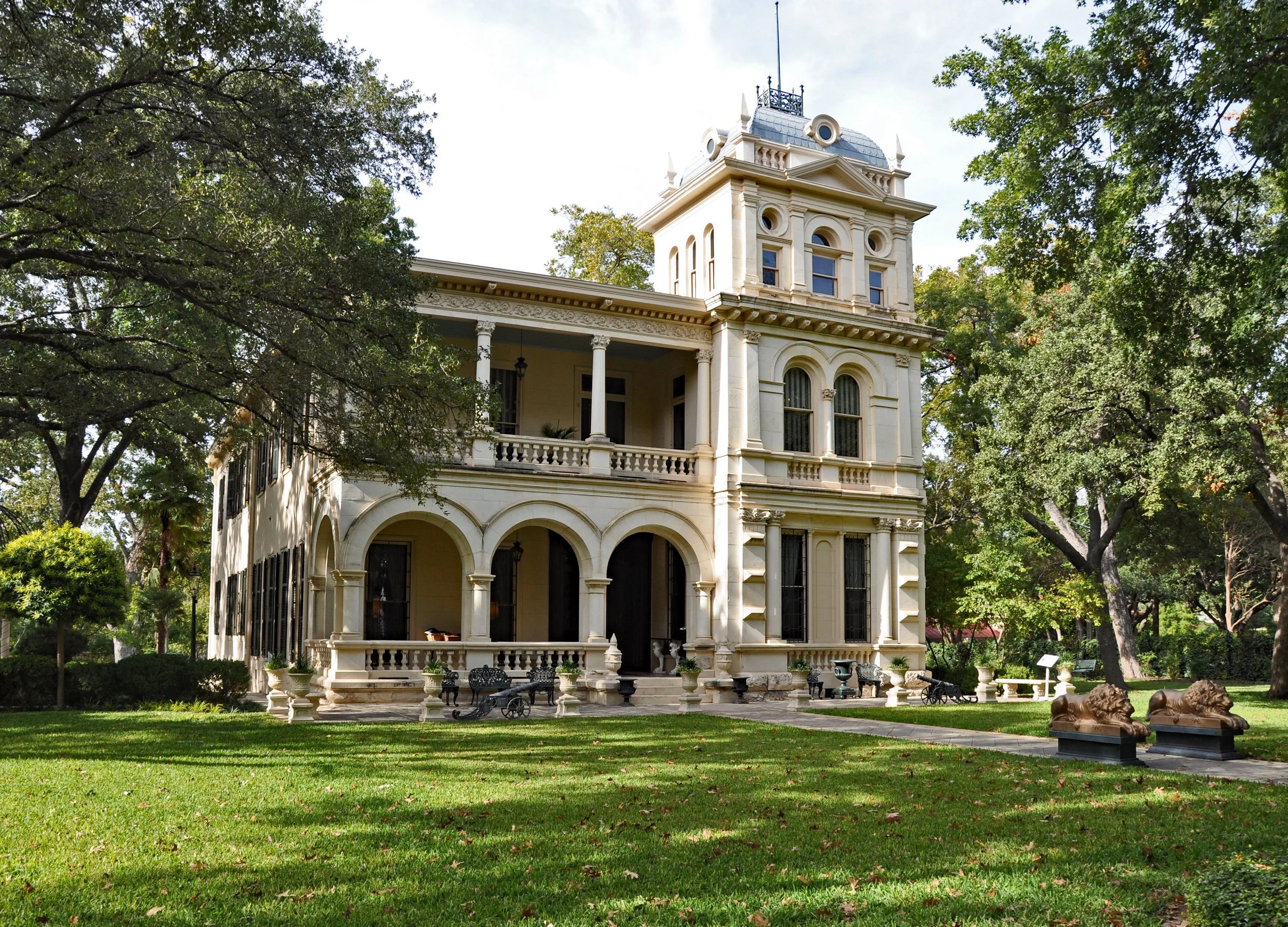 A large cream mansion with a lawn, cannon and ornamental lions in King William Historic District. Drives & Detours San Antonio River Walk hidden gems