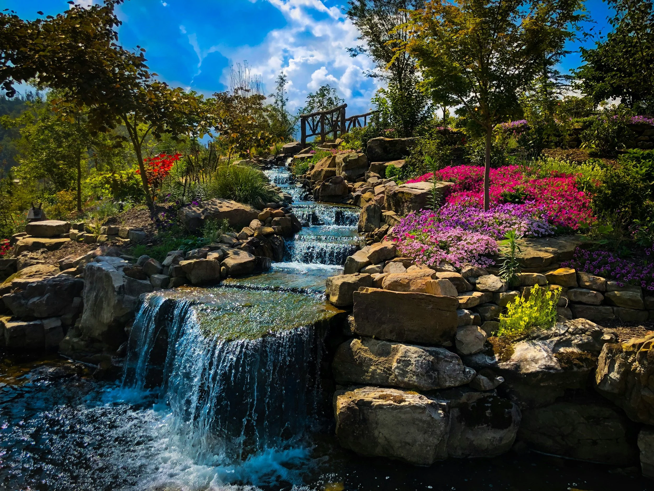 A small manicured waterfall is surrounded by flowers and trees in Gatlinburg, Tennessee. Drives & Detours Great Smoky Mountains first time