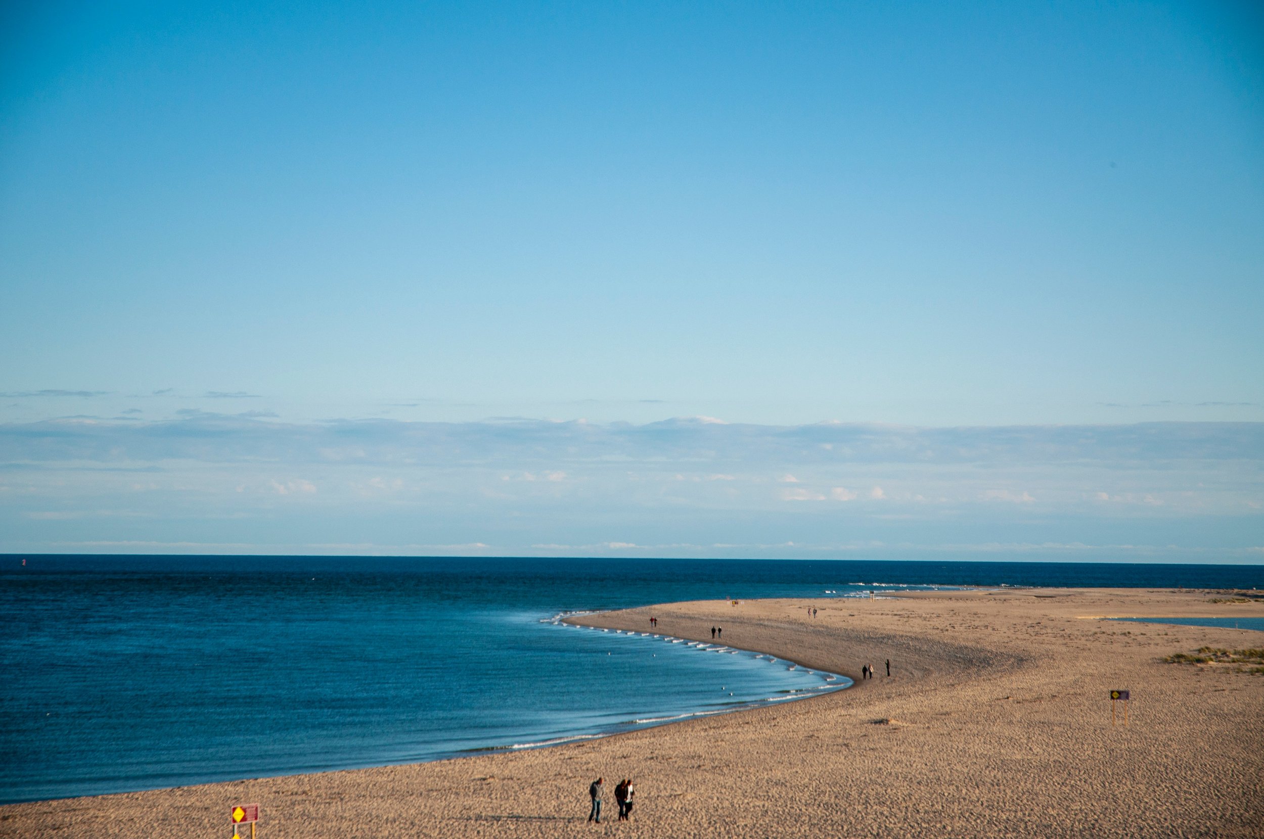 People stroll along a beach in New England. Drives & Detours New Bedford walking tour