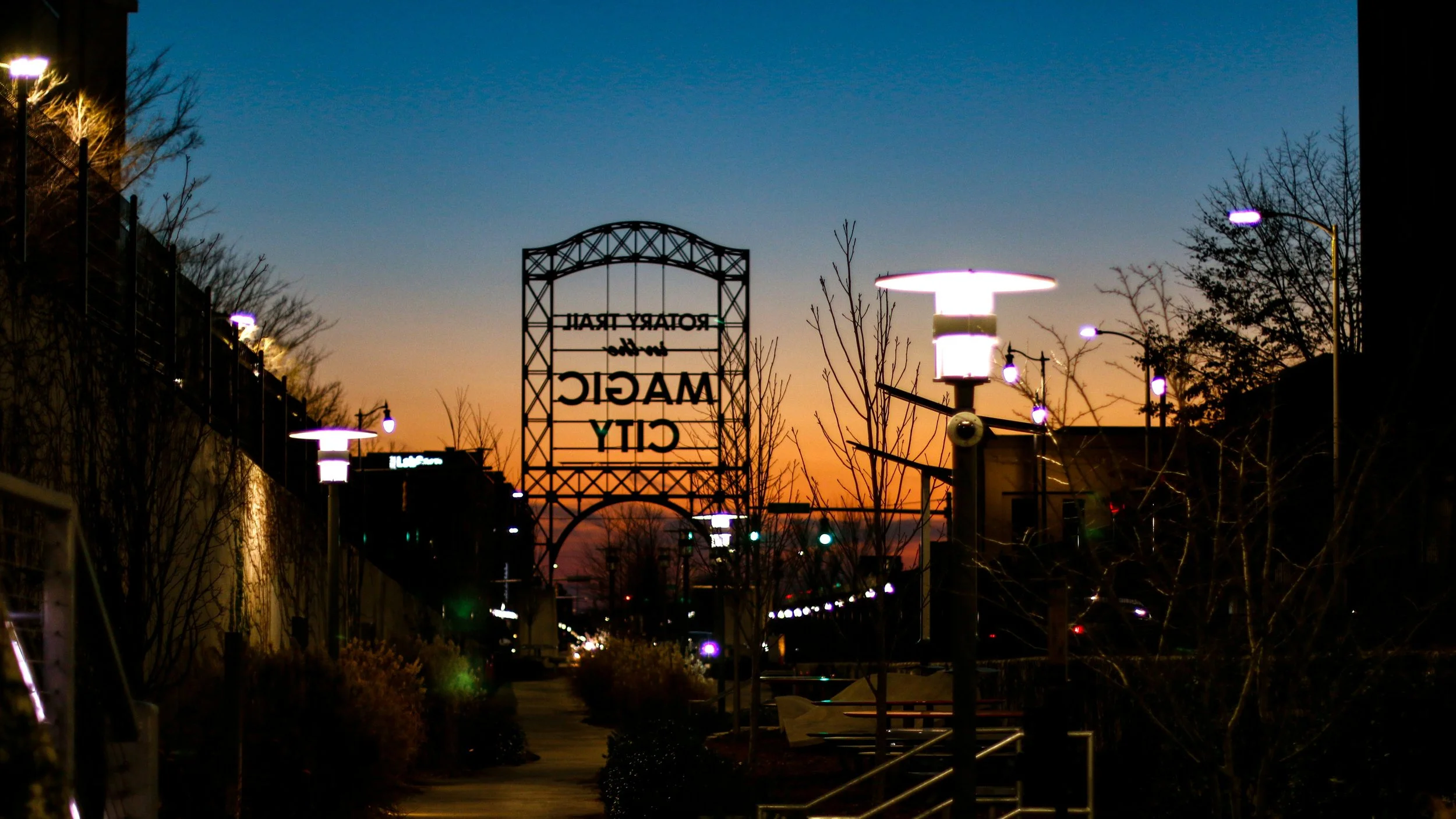 A large iron sign in Birmingham, Alabama, reads: Magic City. It's dusk and the sky is a gradient of oranges and dark blues