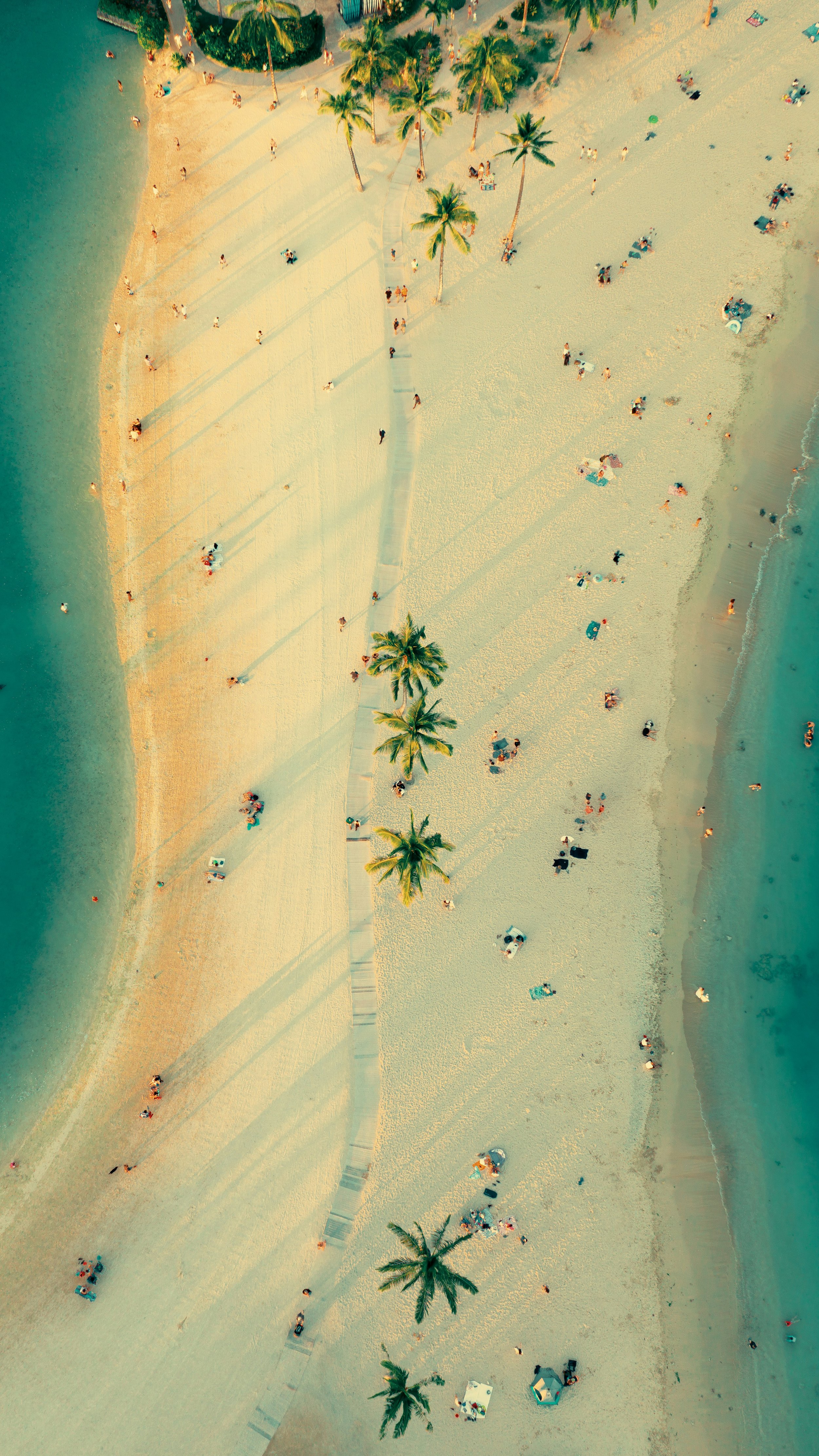 People walk along a beach in Honolulu in an aerial shot. Drives & Detours Waikīkī walking tour
