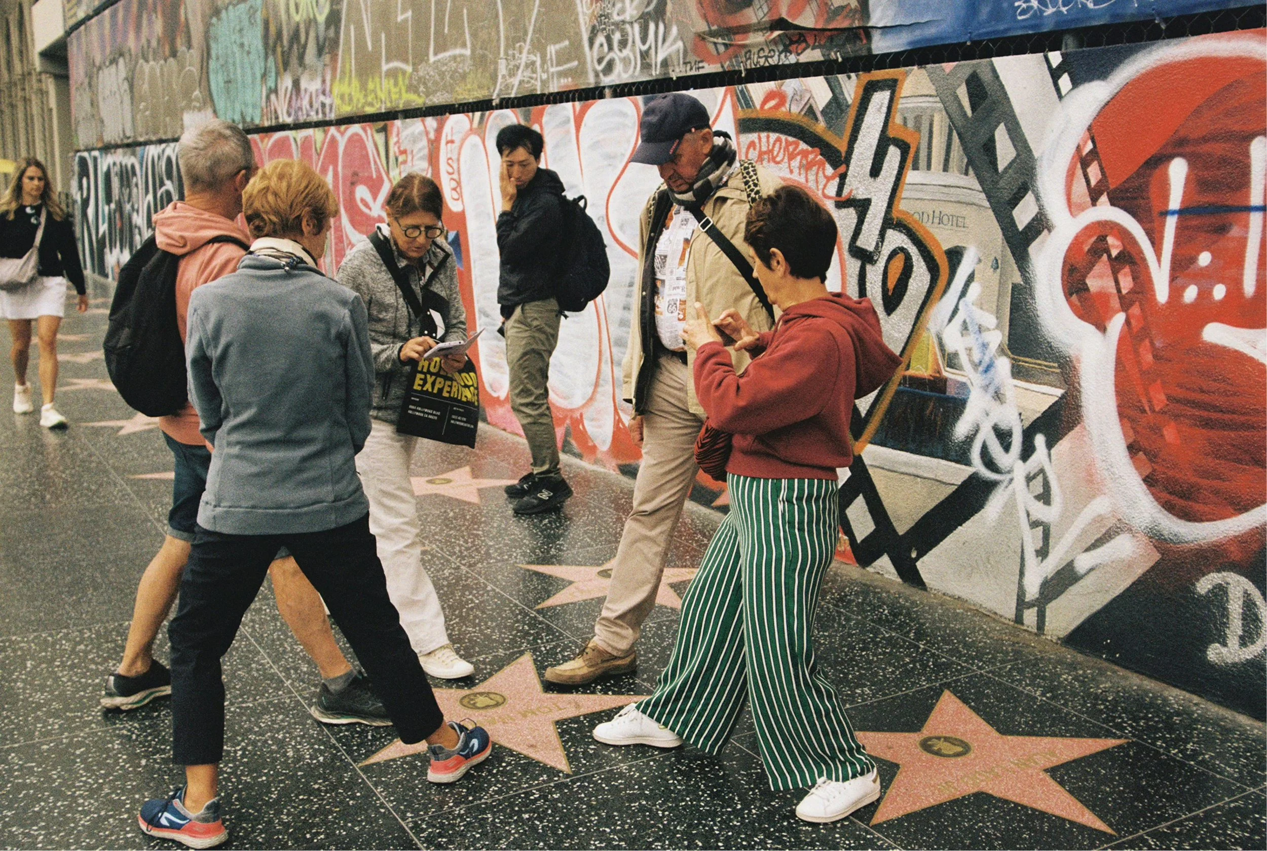People pose for a picture with their feet and a star on the walk of fame in Los Angeles. Drives & Detours Hollywood Audio Tour