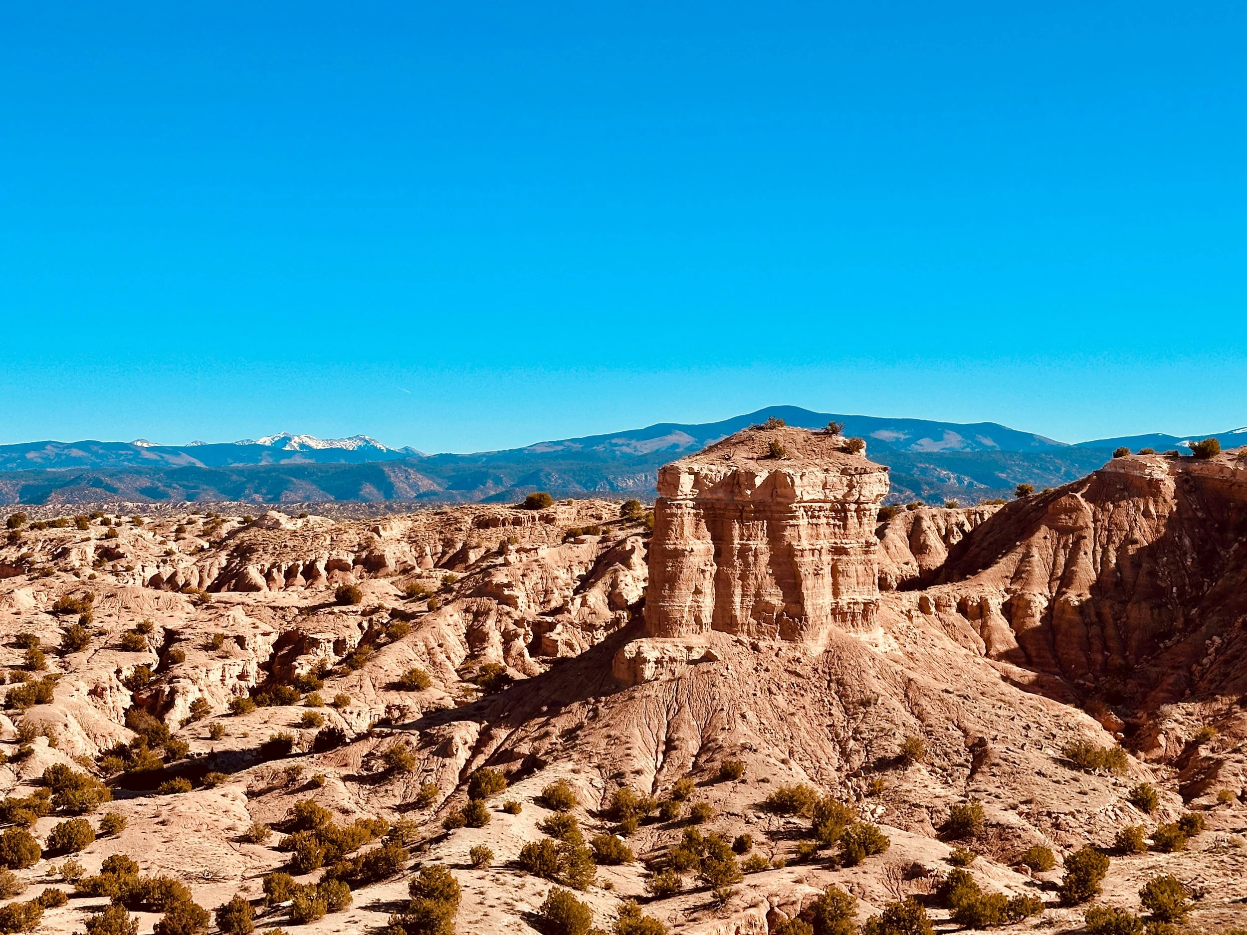 Rock formations and snowcapped mountains under a blue sky. Drives & Detours first-timers guide Santa Fe