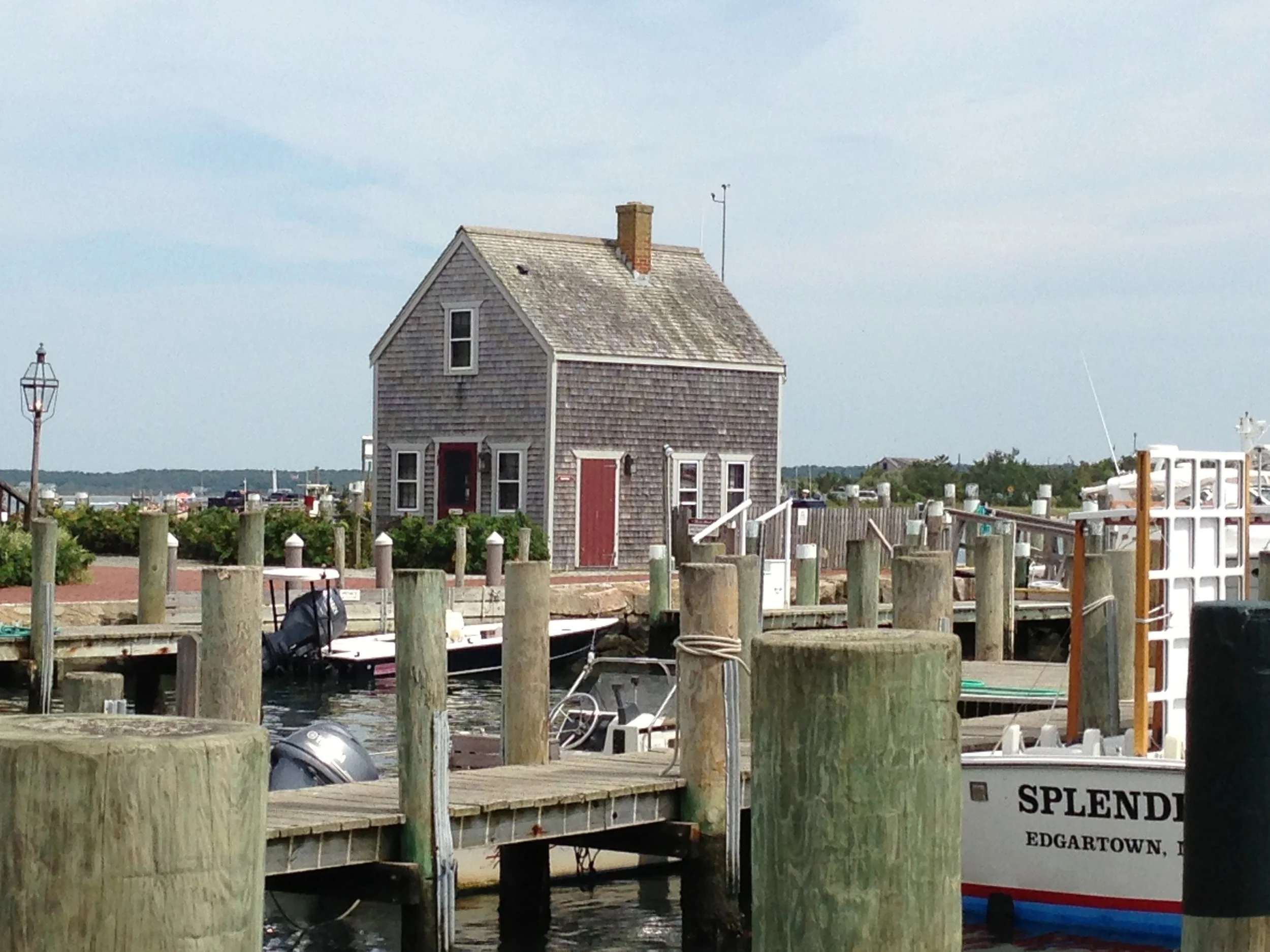 A wooden house with a red door sits in the middle of docks in Menemsha Harbor. Drives & Detours things to do in Martha's Vineyard