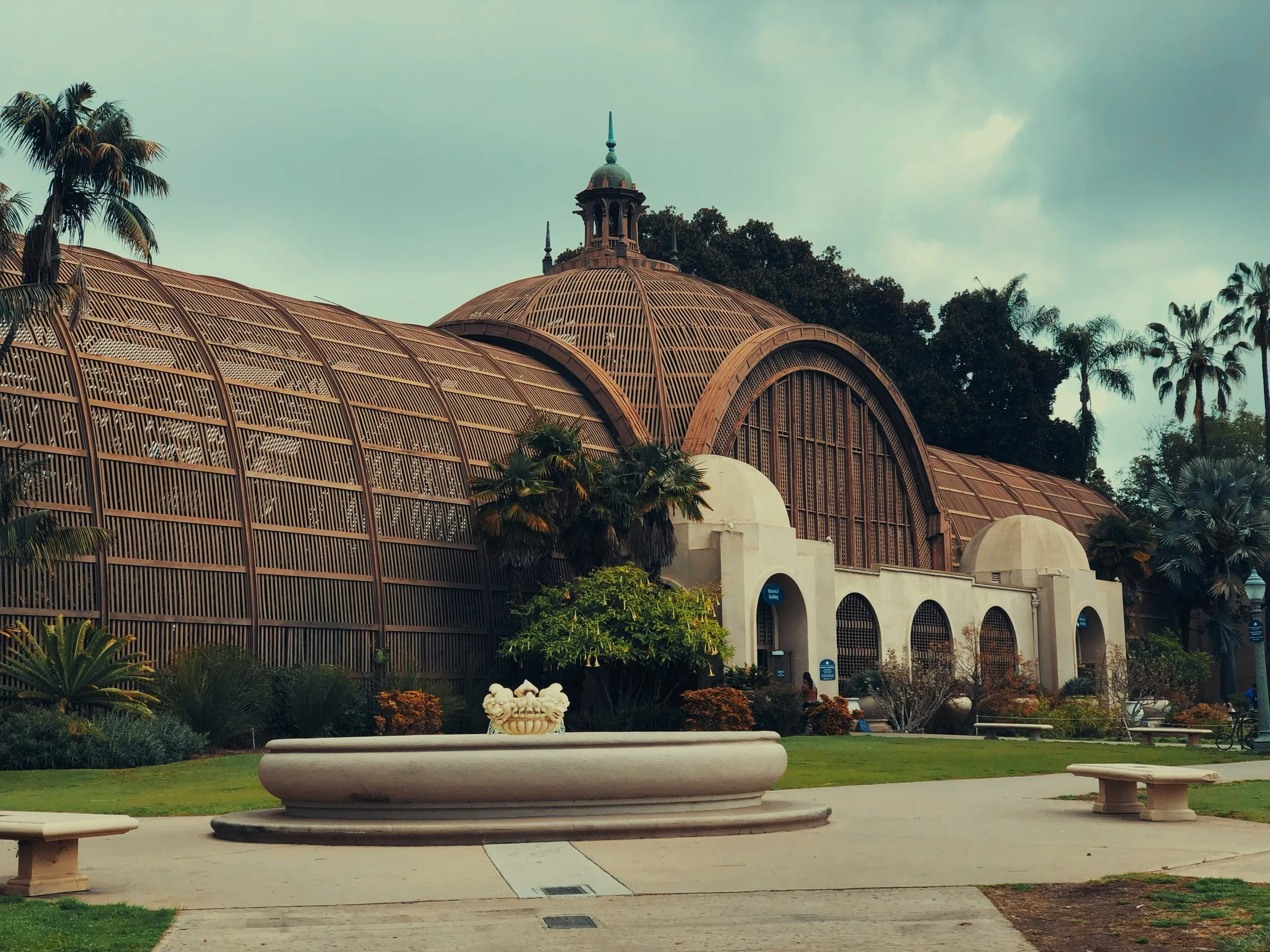 The exterior of the Botanical Building in Balboa Park, San Diego. The iron structure create a dome and two large tunnels. Through the glass, you can just about see some of the plants inside